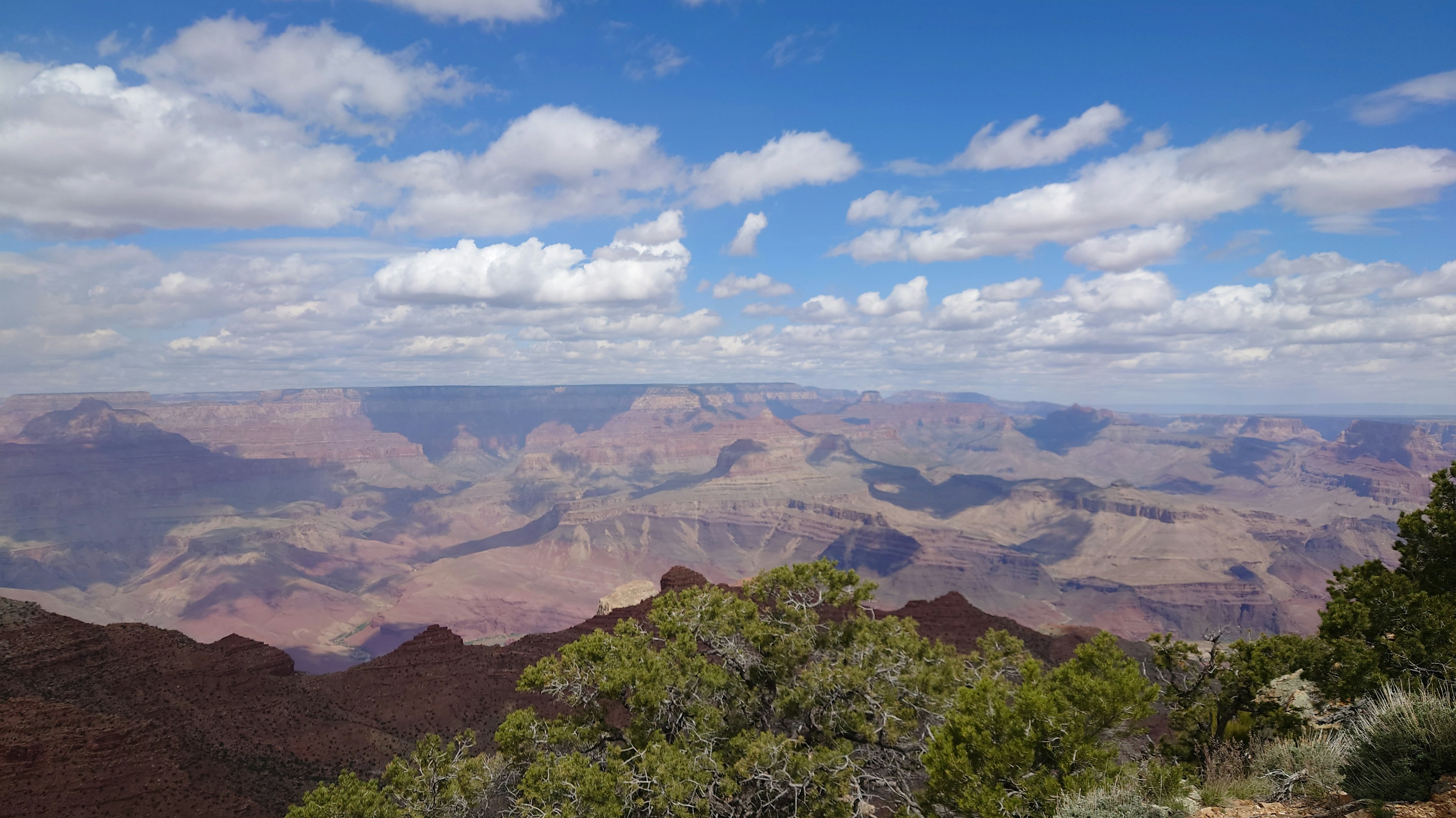 Khung cảnh rộng lớn của Grand Canyon với bầu trời xanh và mây