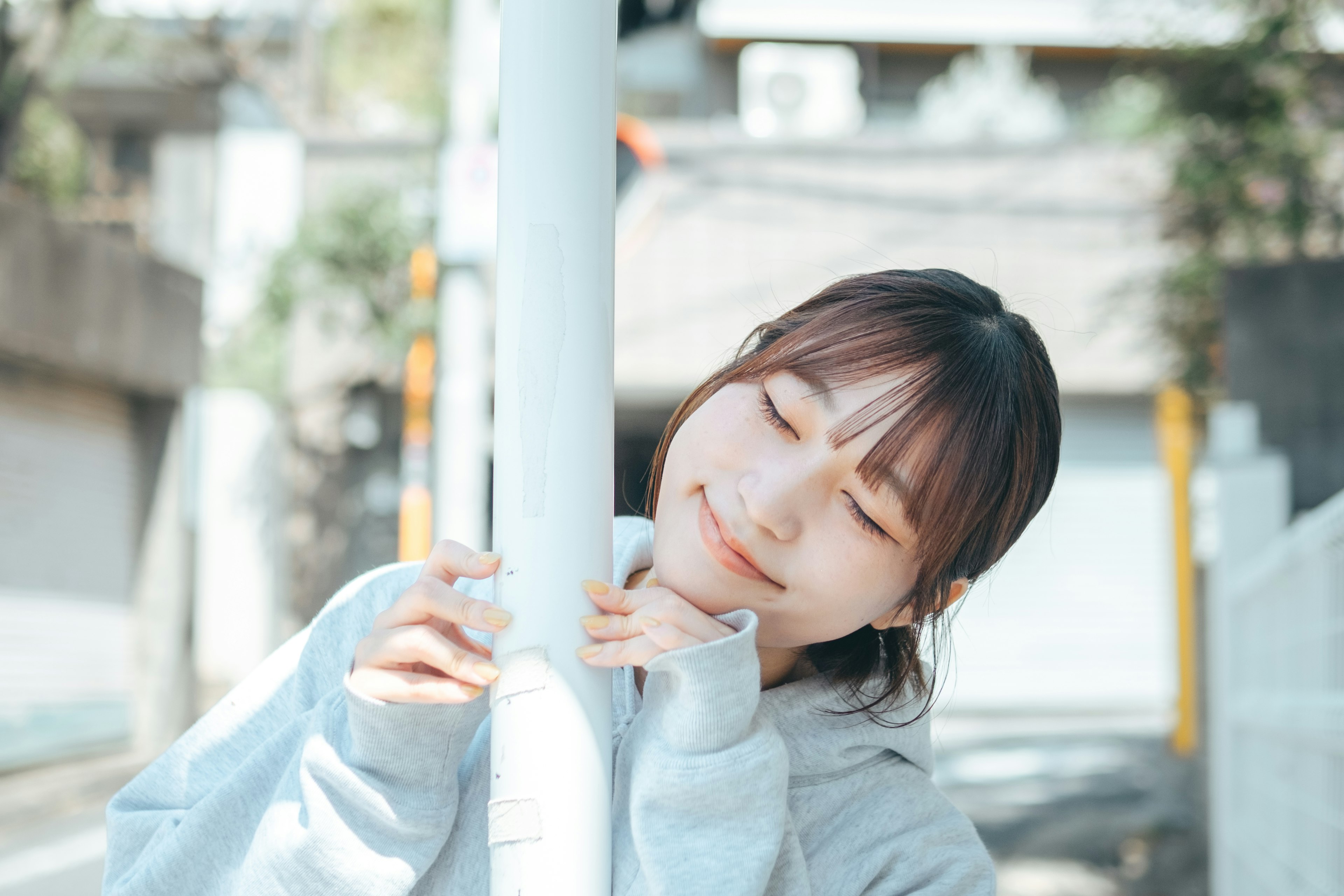 Young woman leaning against a street pole smiling