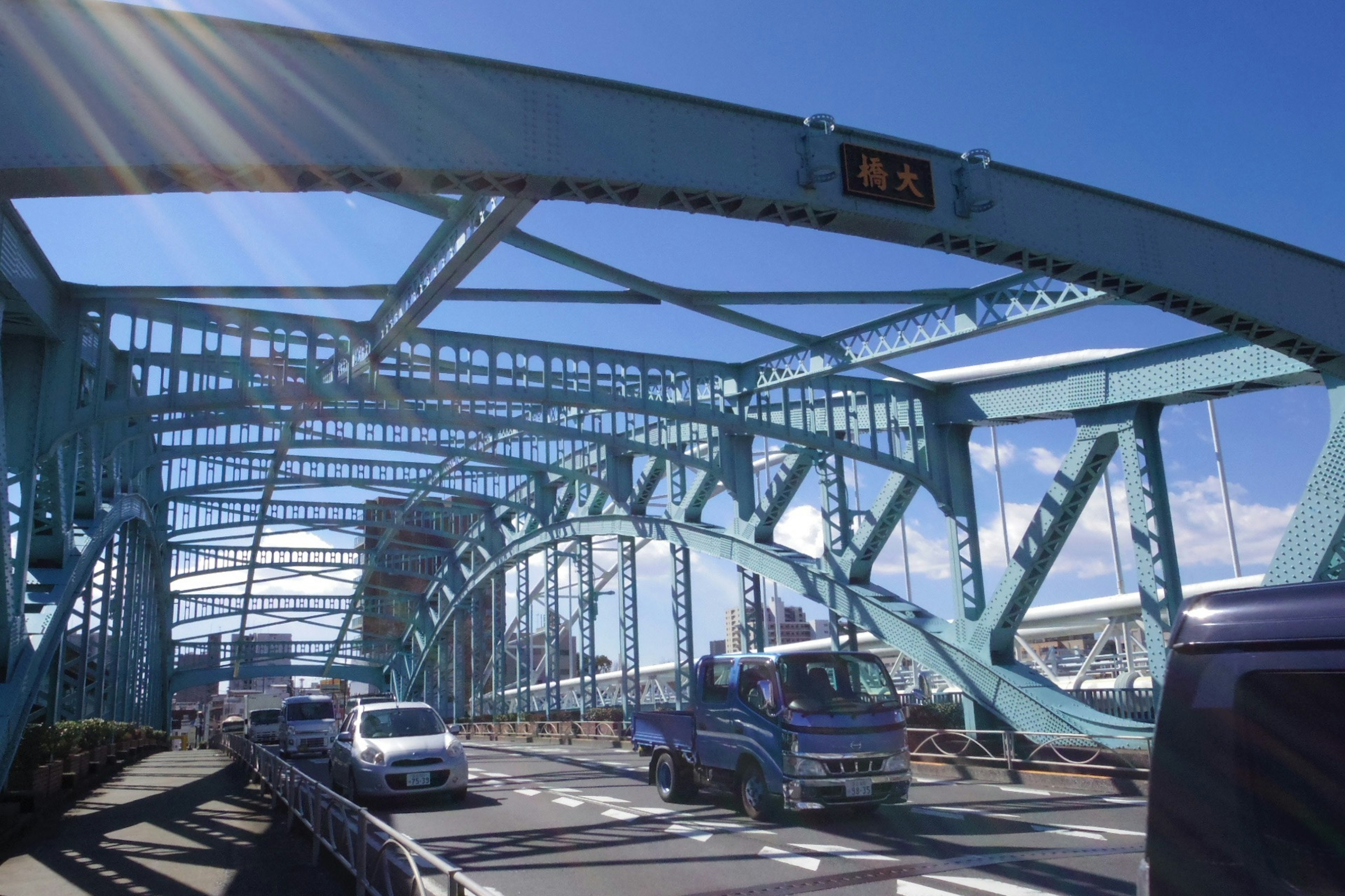 Blue arch bridge with vehicles and clear sky