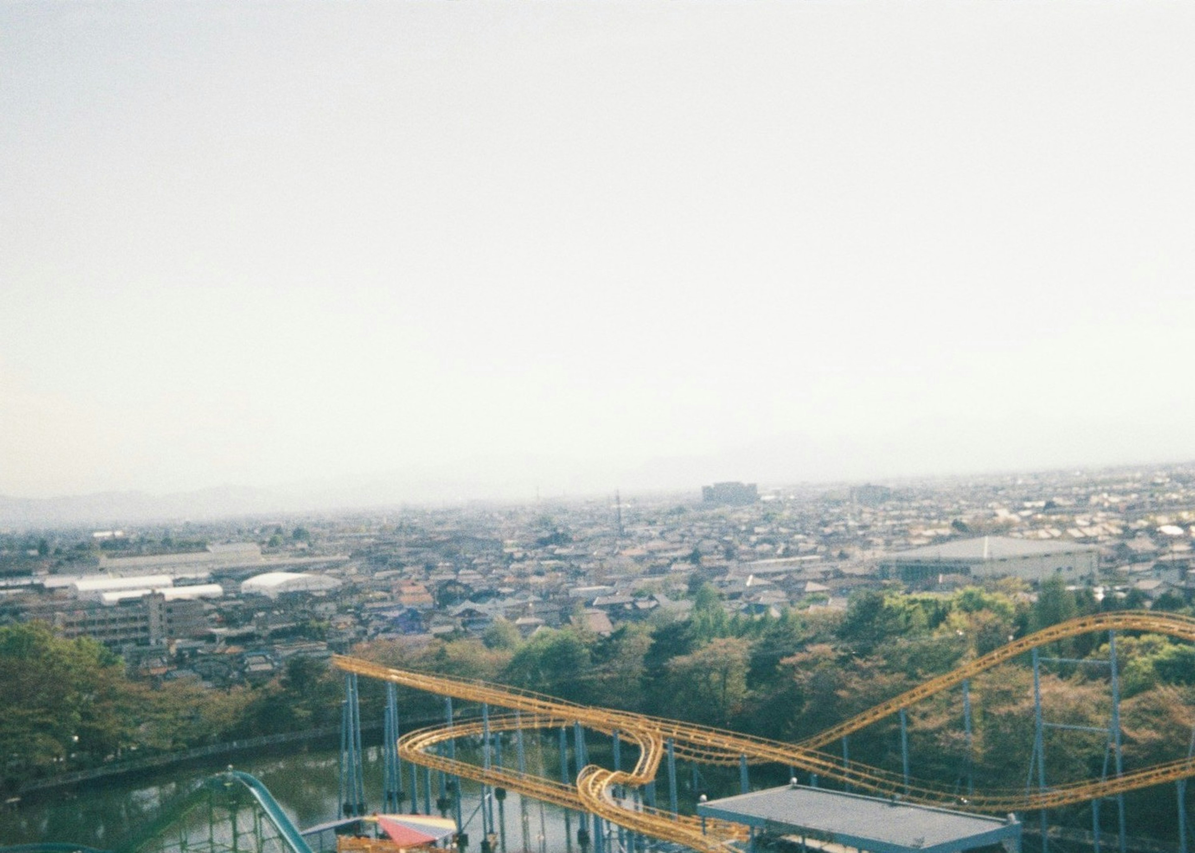 View of a cityscape with a roller coaster and greenery