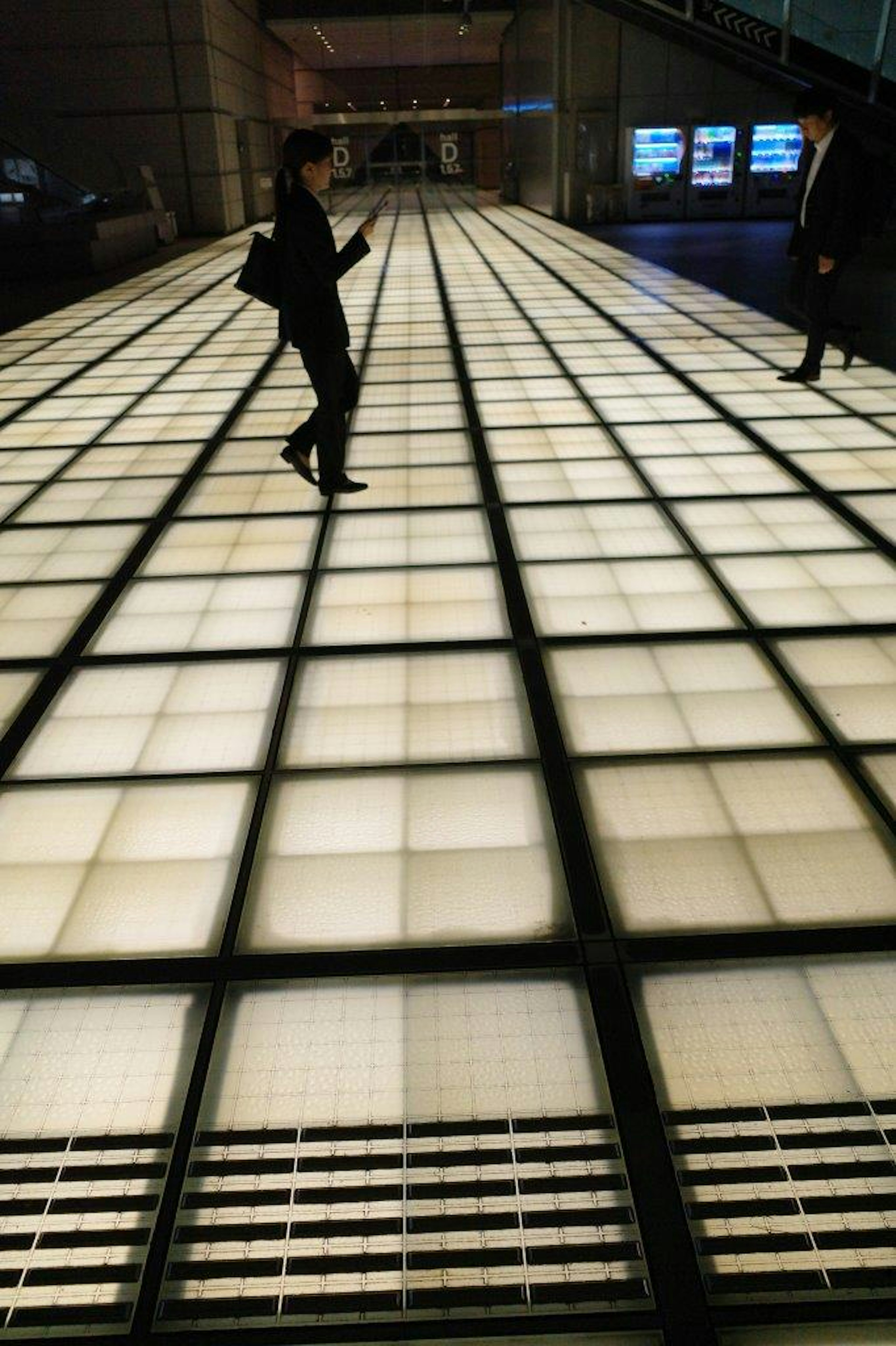 Des personnes marchant sur un sol à motifs de grille lumineux