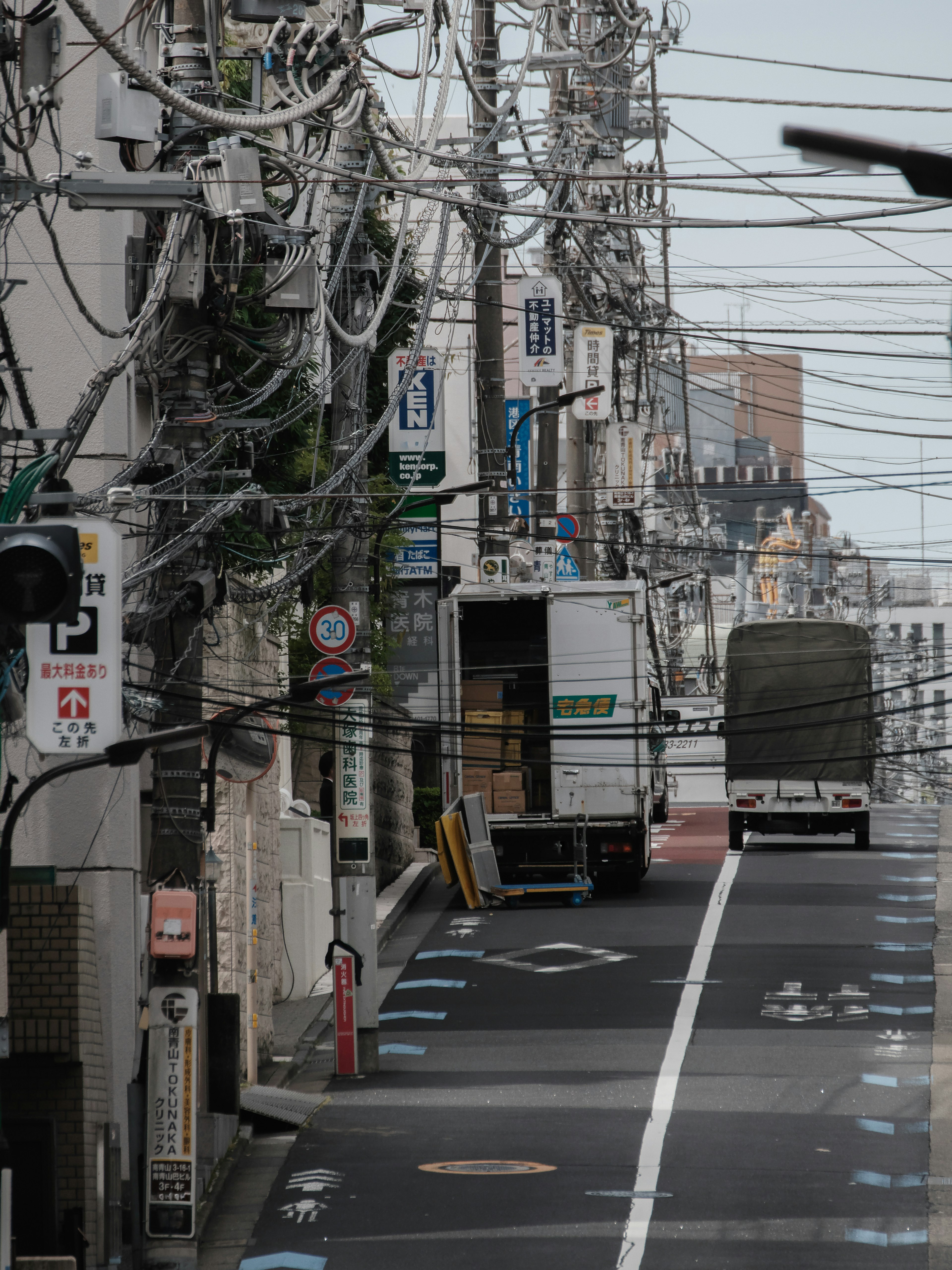 Calle estrecha con camión estacionado y líneas eléctricas arriba