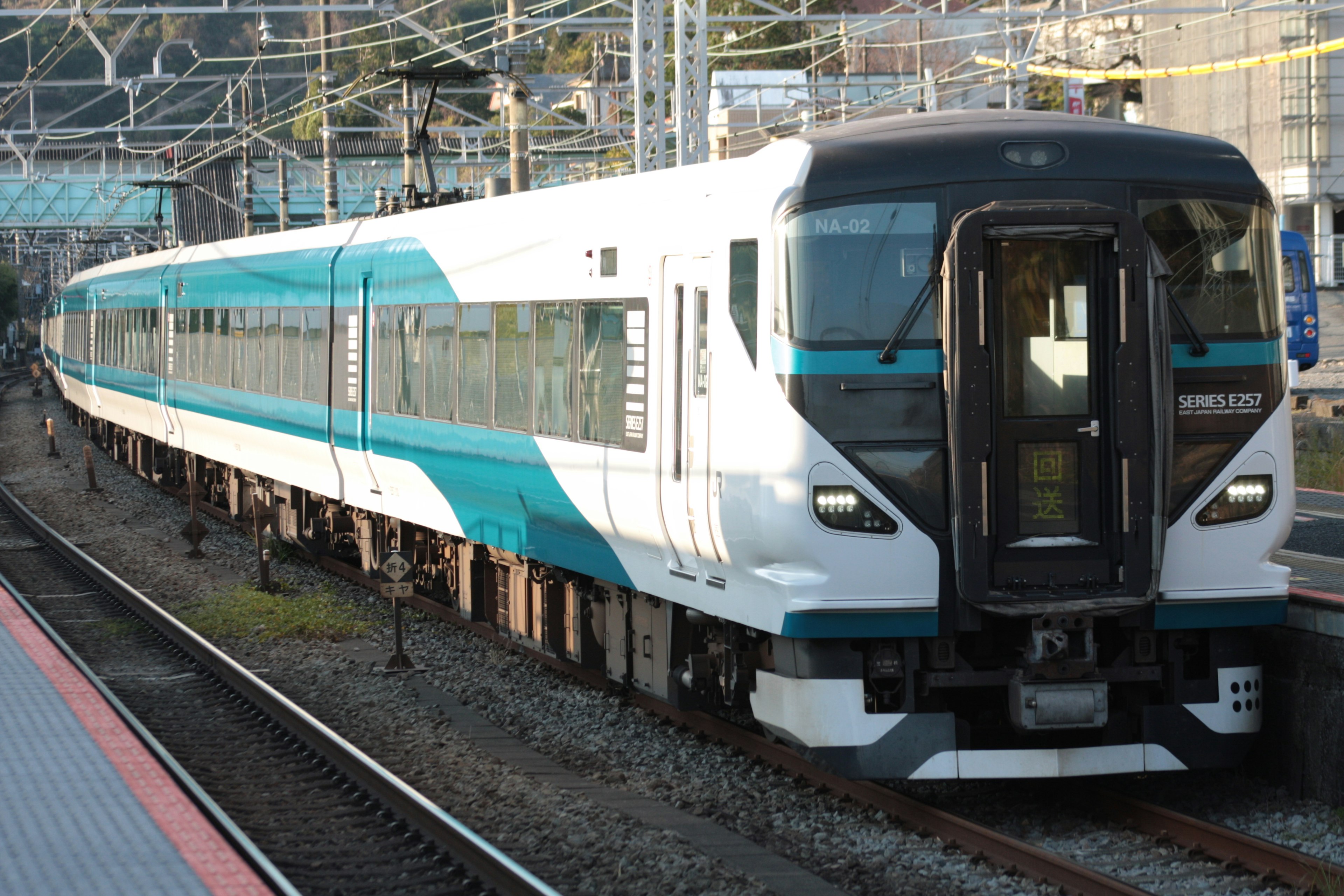 Sebuah kereta dengan desain biru dan putih berhenti di stasiun