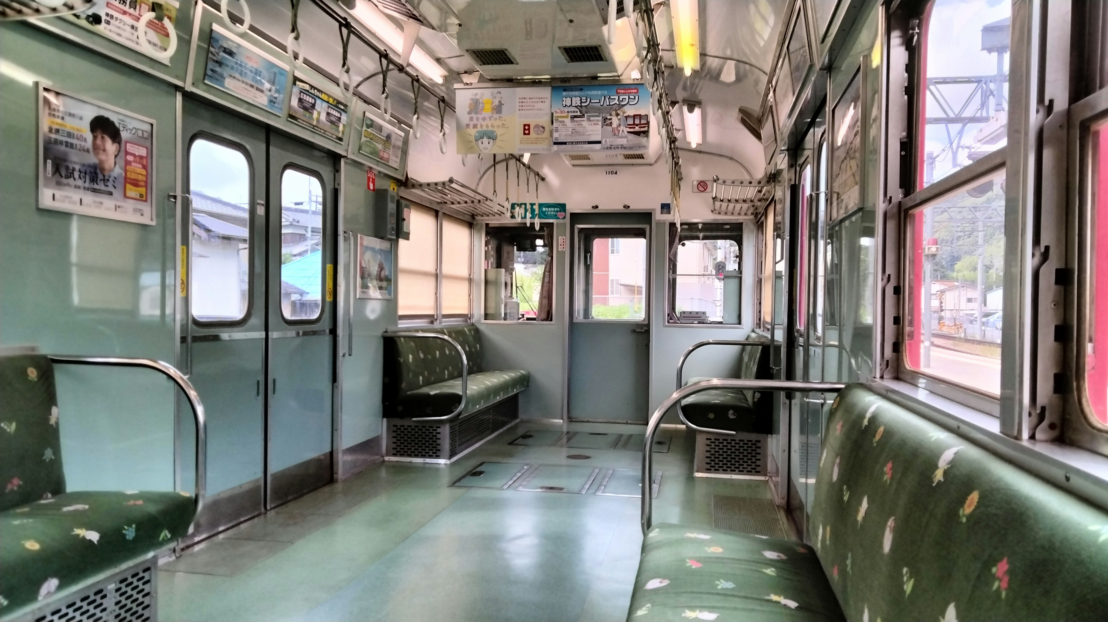 Interior de un vagón de tren vacío con asientos verdes y luz natural de las ventanas