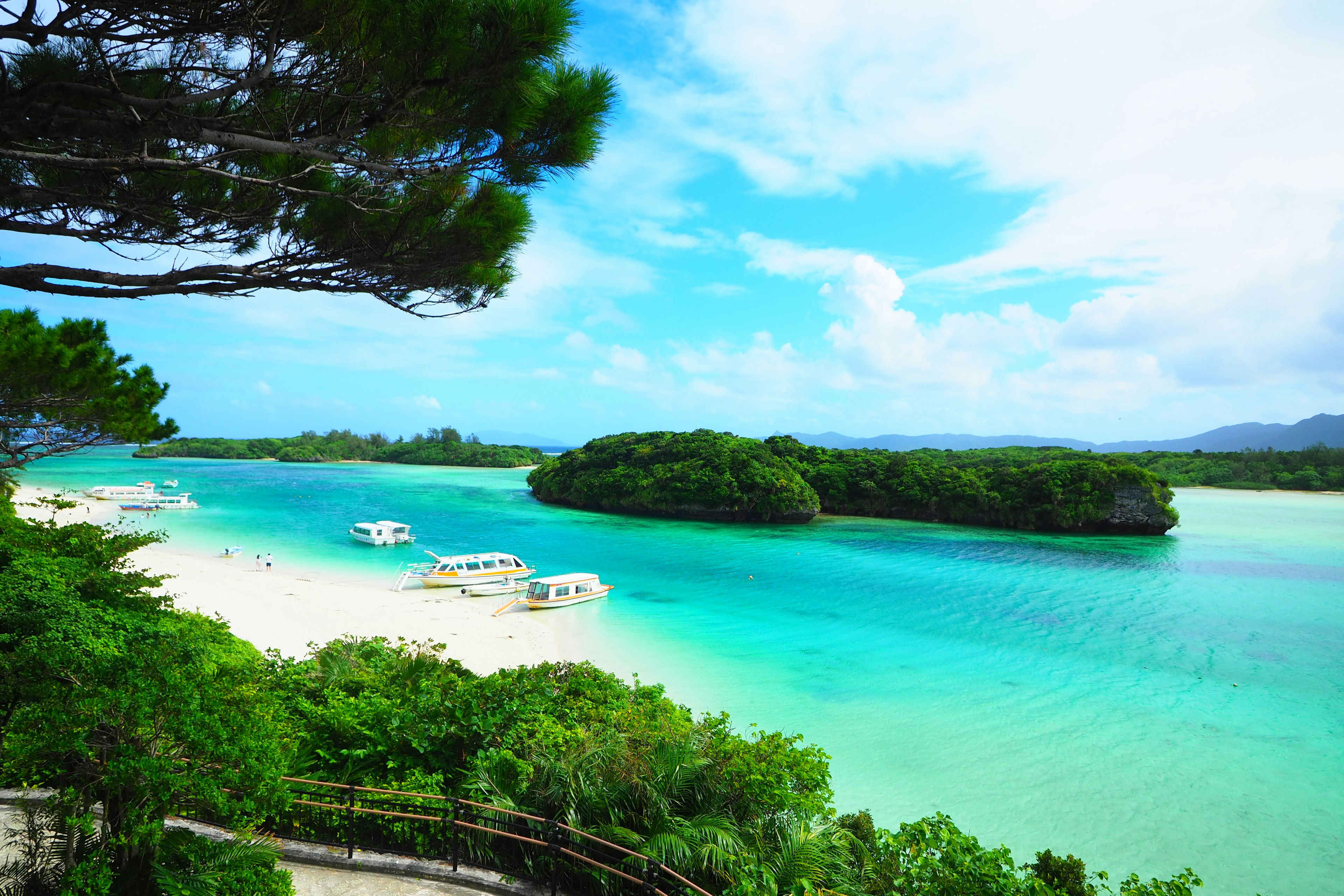 ทิวทัศน์ที่สวยงามพร้อมทะเลสีน้ำเงินและชายหาดทรายขาวที่มีเรือ