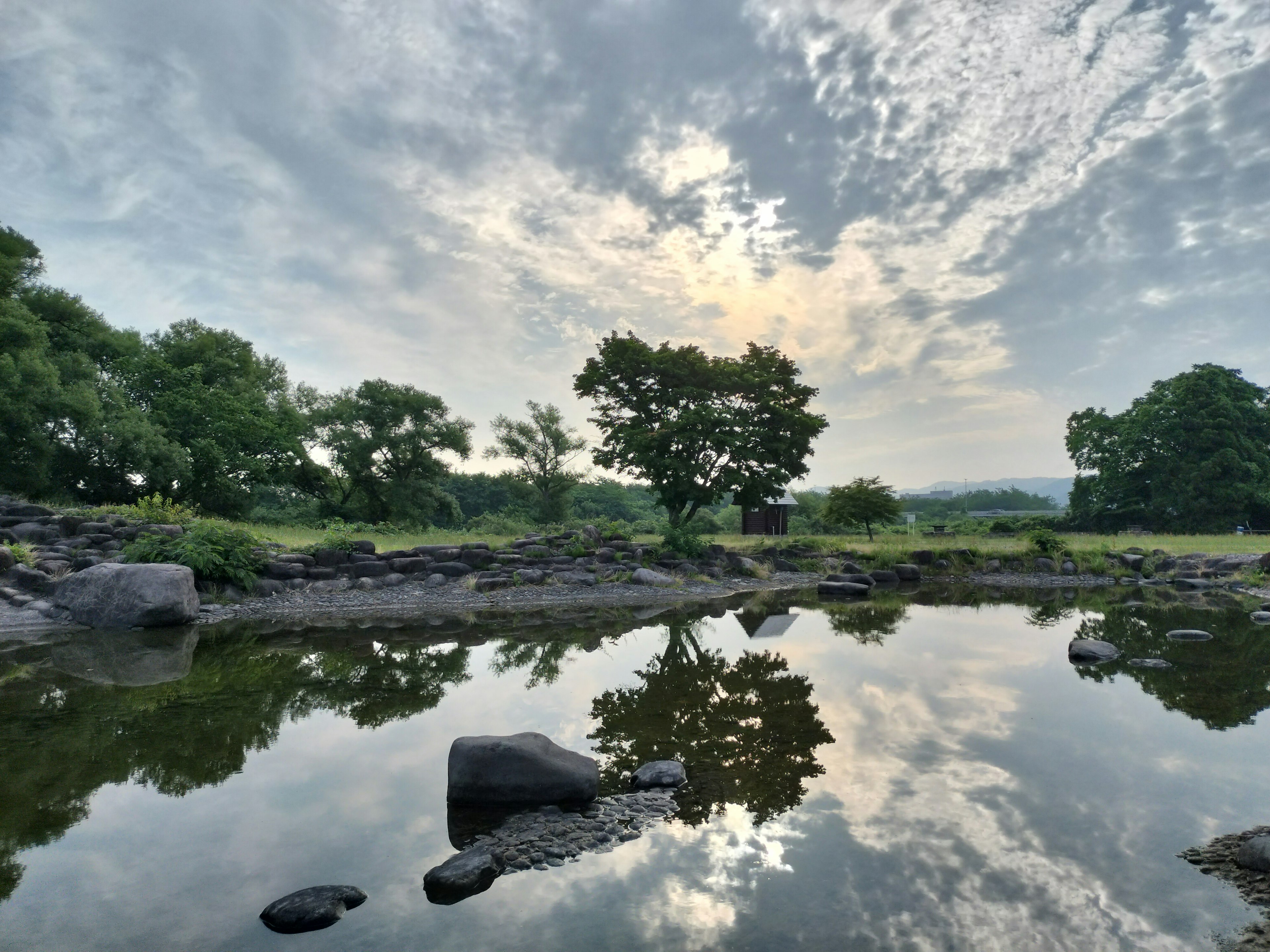 Paesaggio sereno con alberi e nuvole riflessi nell'acqua calma