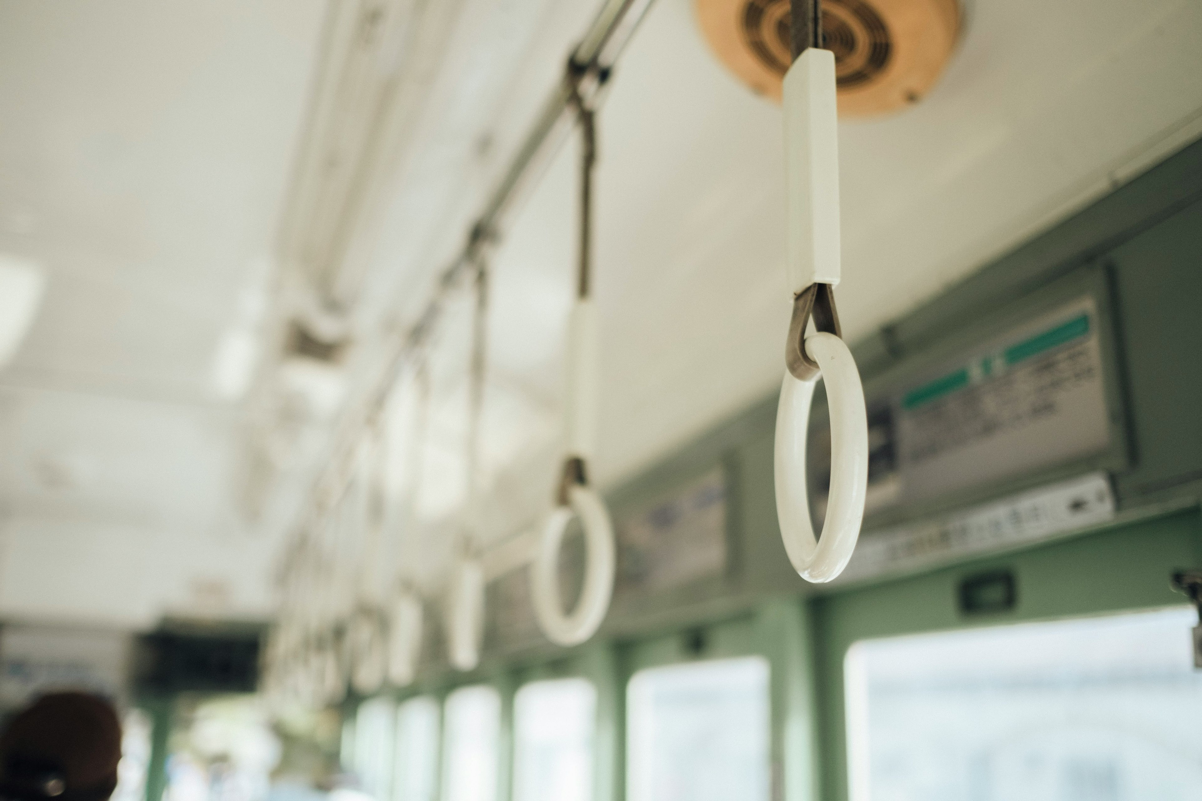 Interno di un treno con anelli bianchi appesi e pannelli verdi