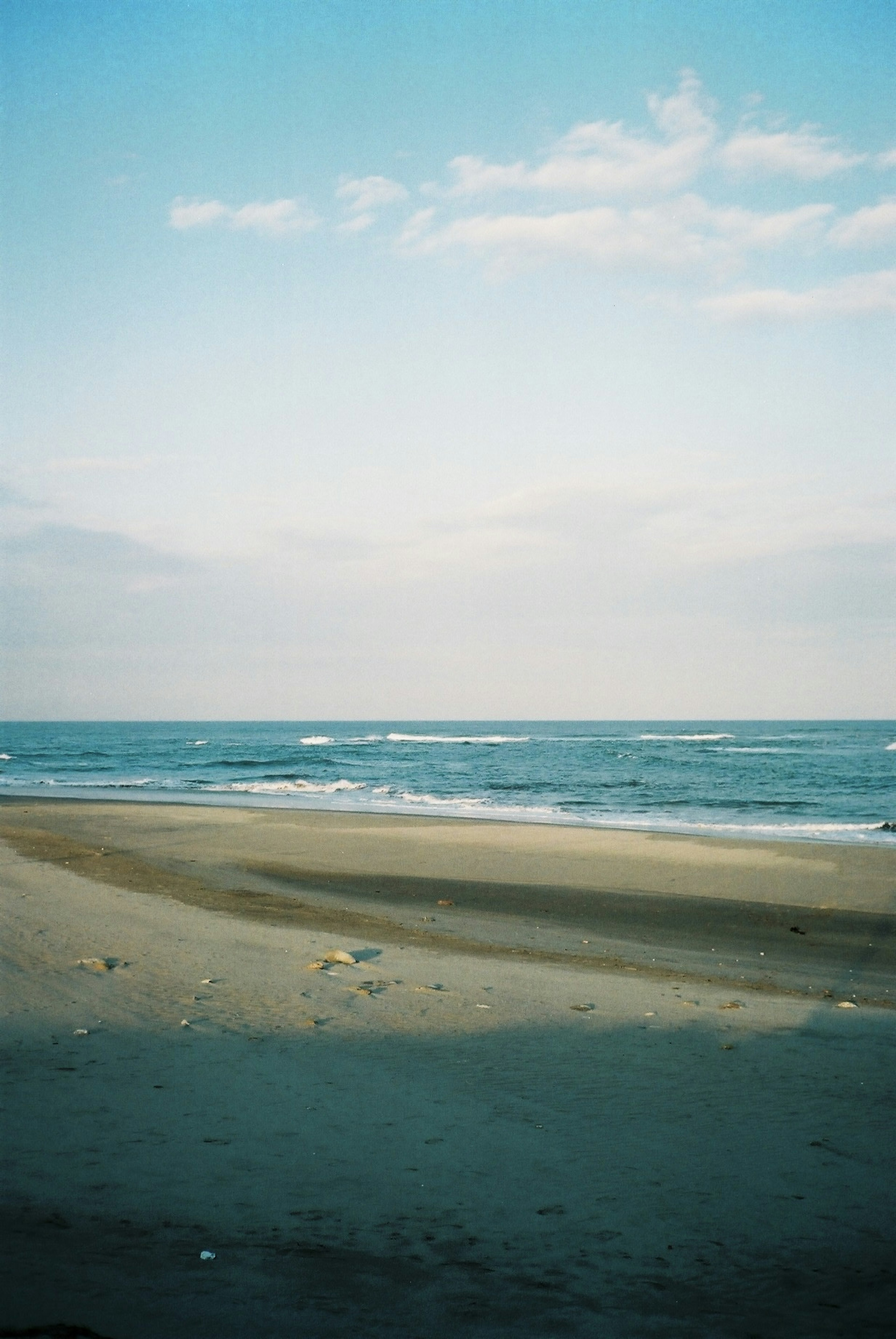 ทิวทัศน์ชายหาดที่มีท้องฟ้าสีฟ้าและทะเลสงบ