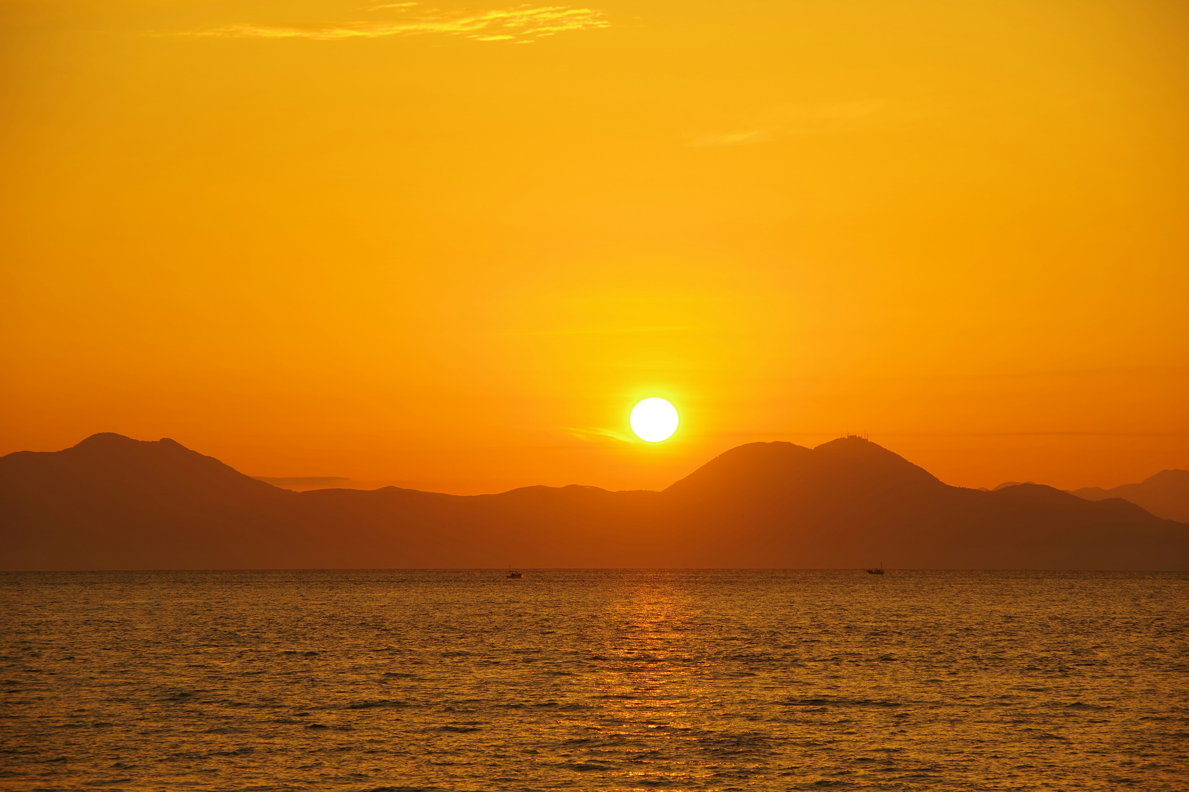 Wunderschöne Landschaft mit Sonnenuntergang über dem Meer und Bergsilhouetten