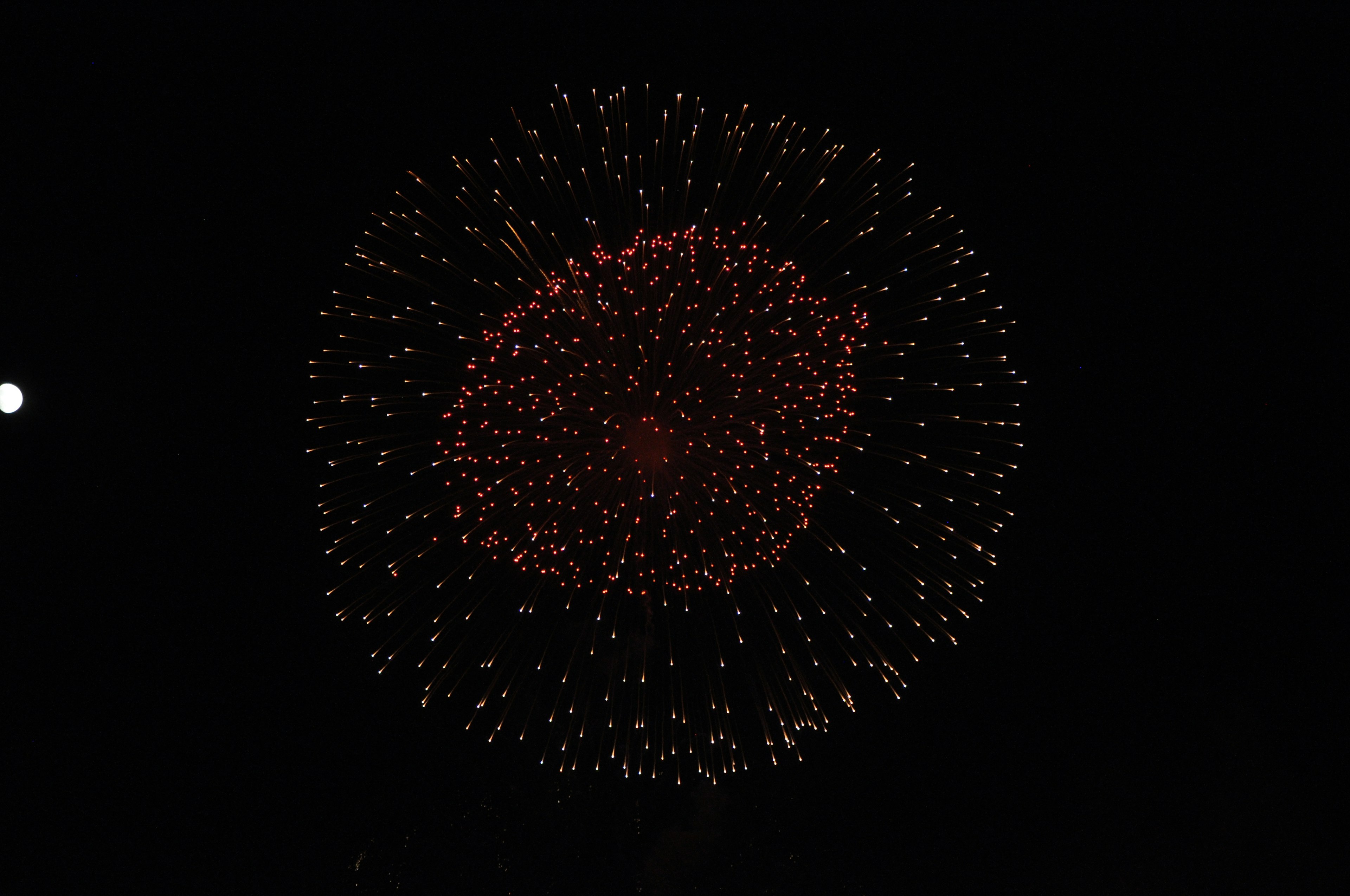 Kreisförmiges Muster von Feuerwerk am Nachthimmel mit roten und gelben Farbtönen