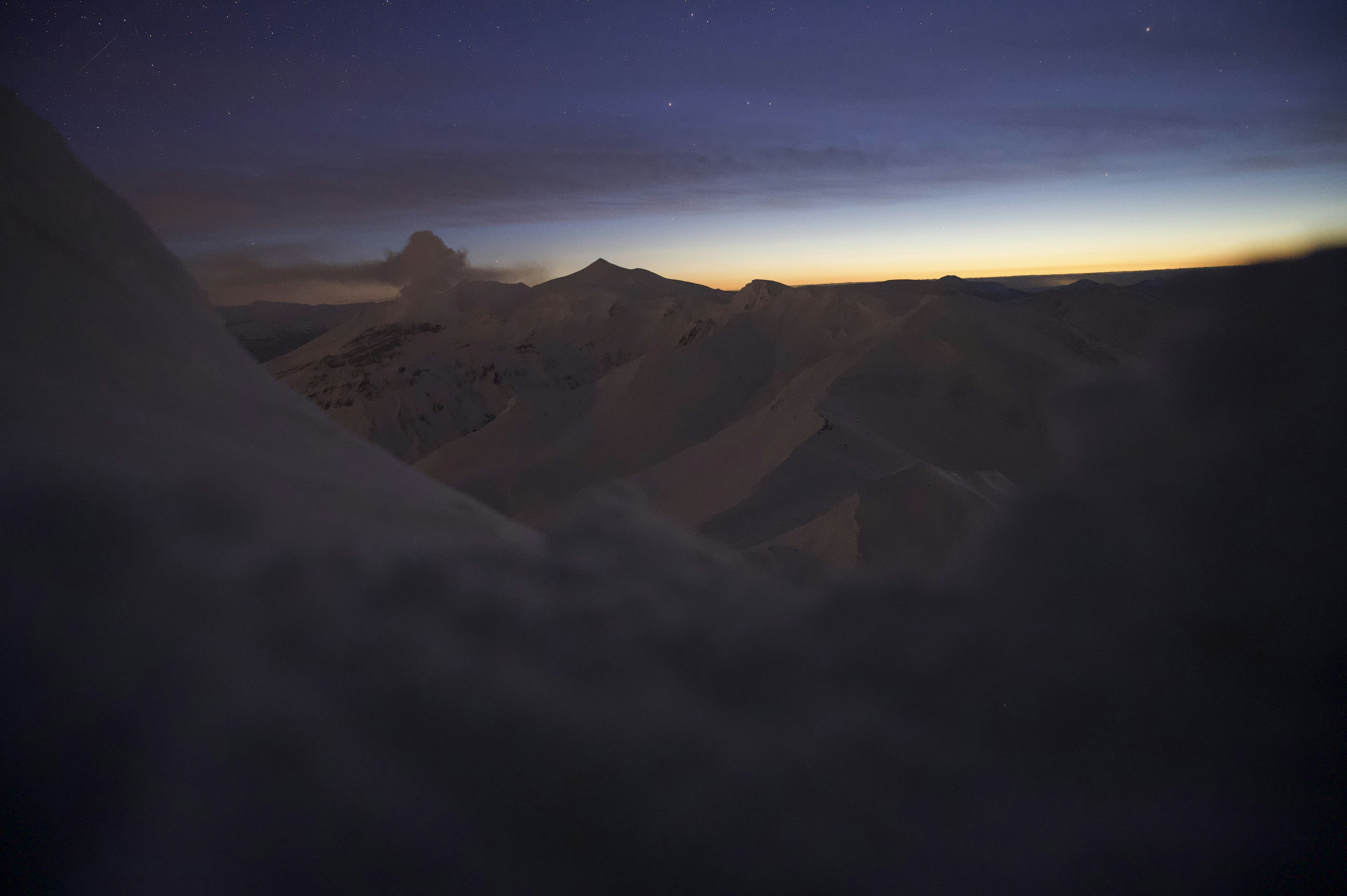 Dim mountain silhouettes with dawn sky