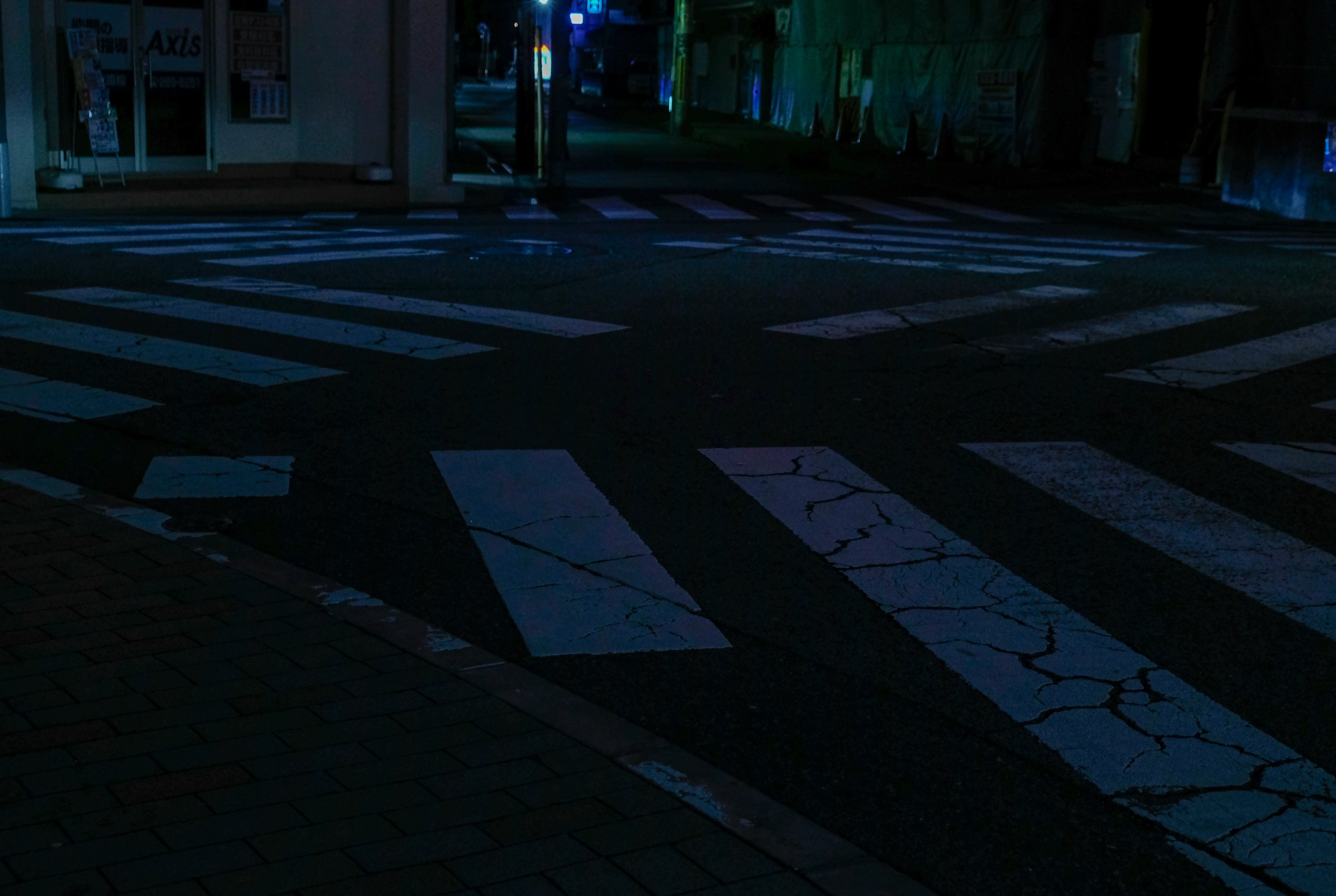 Intersección nocturna con pasos peatonales blancos y un entorno oscuro