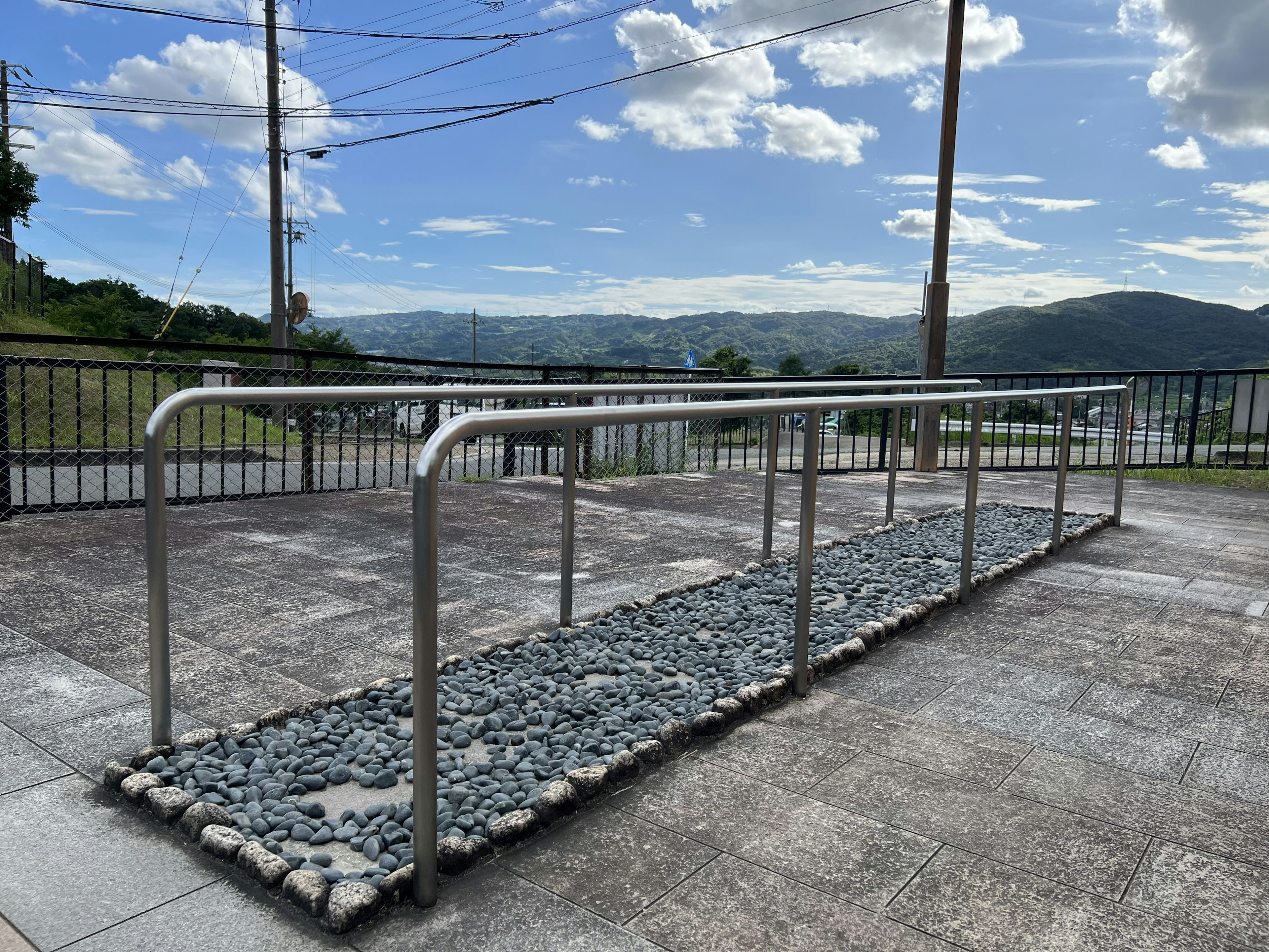 Paisaje con pasamanos sobre un camino de piedras y área pavimentada