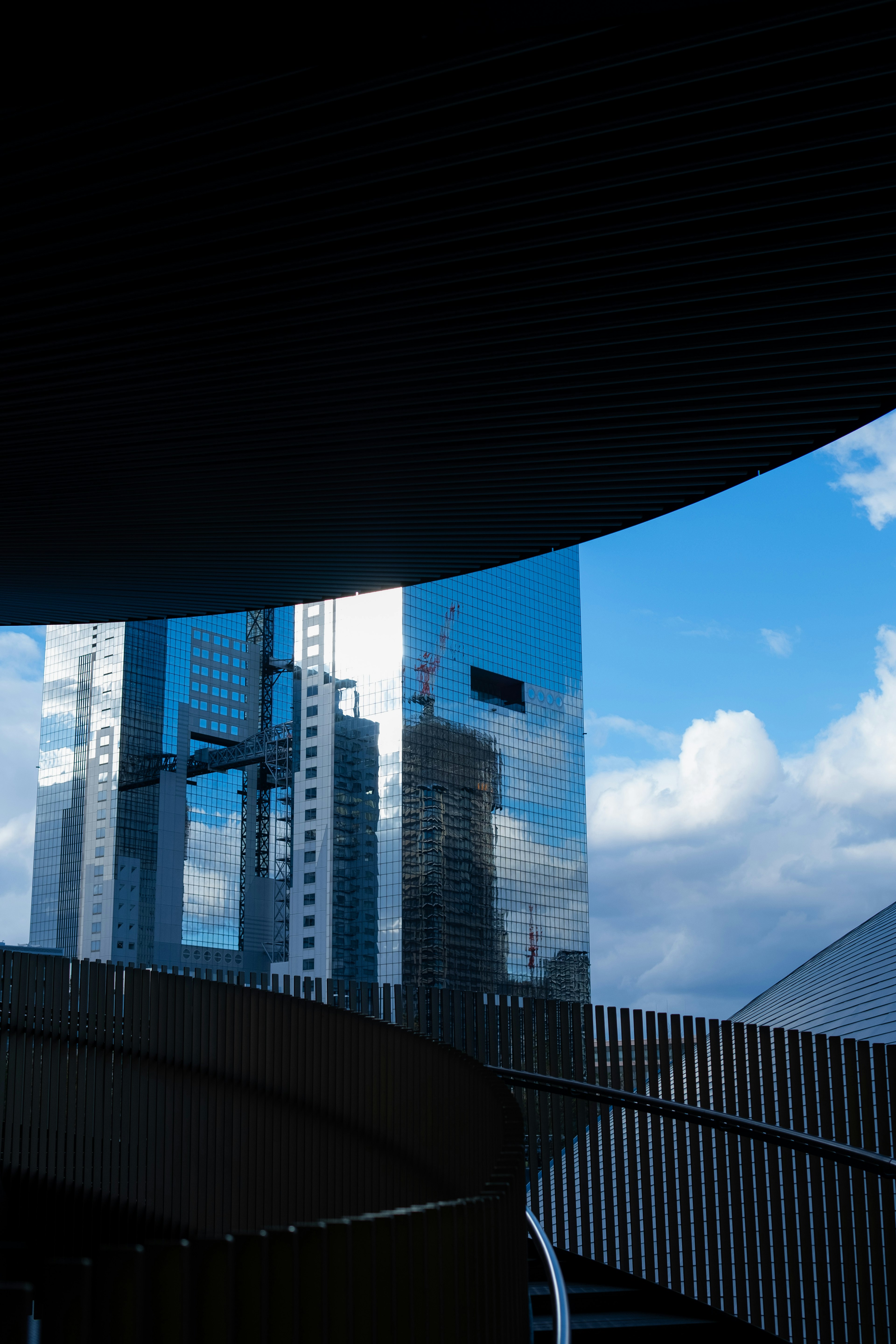 Gambar menunjukkan gedung modern yang memantulkan di bawah langit biru