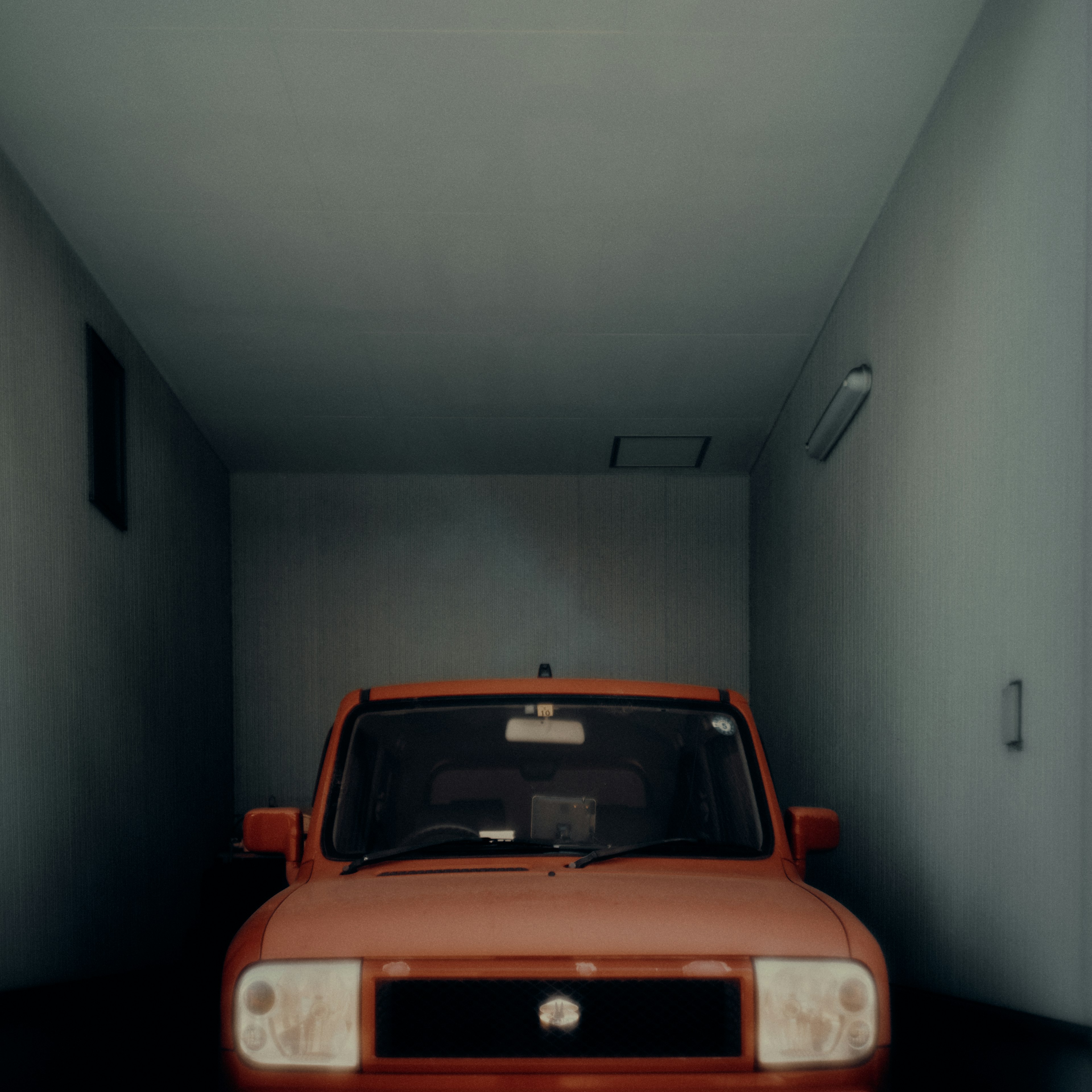 Red car parked in a garage with blue walls