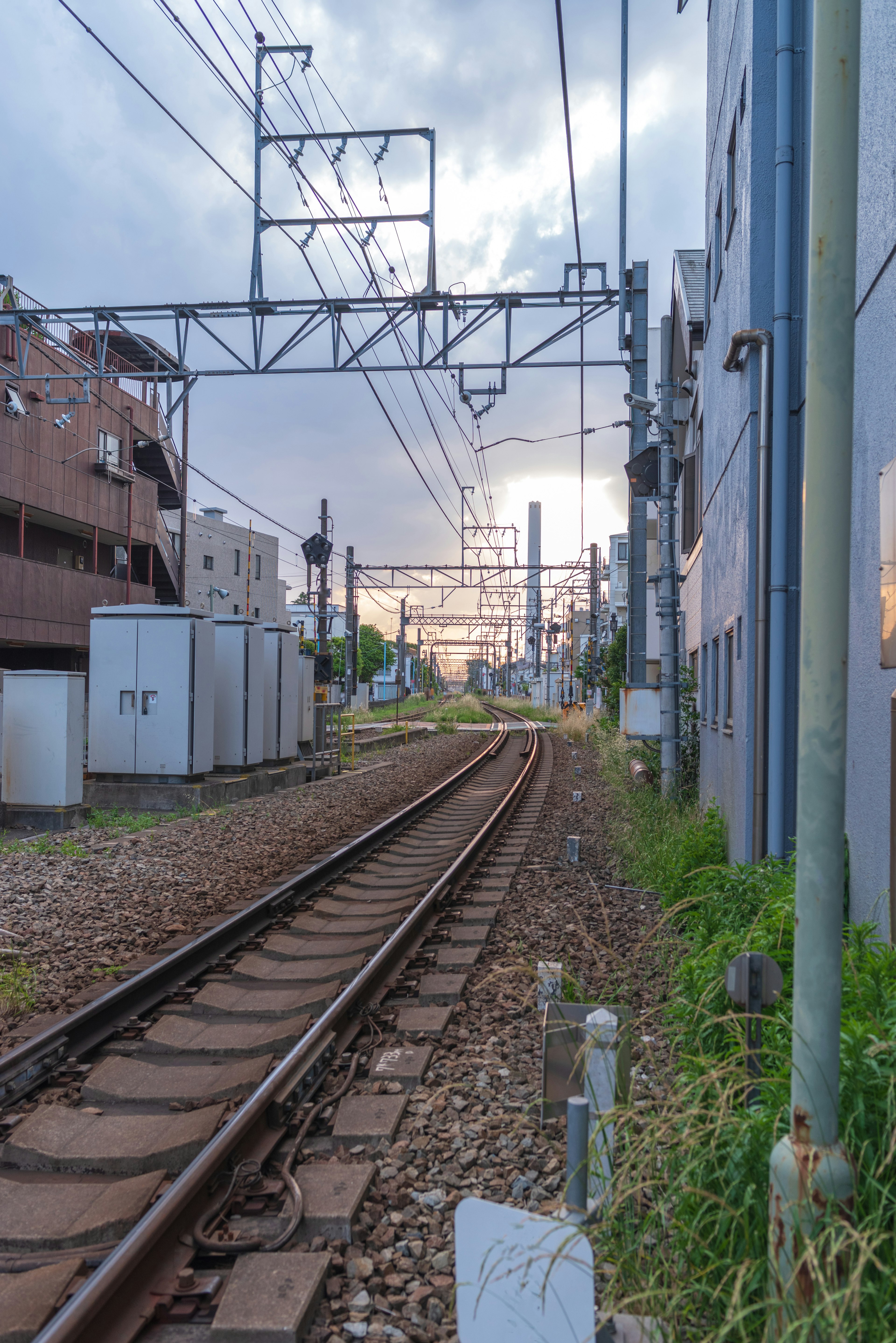 Binari ferroviari con edifici circostanti sotto un cielo al tramonto