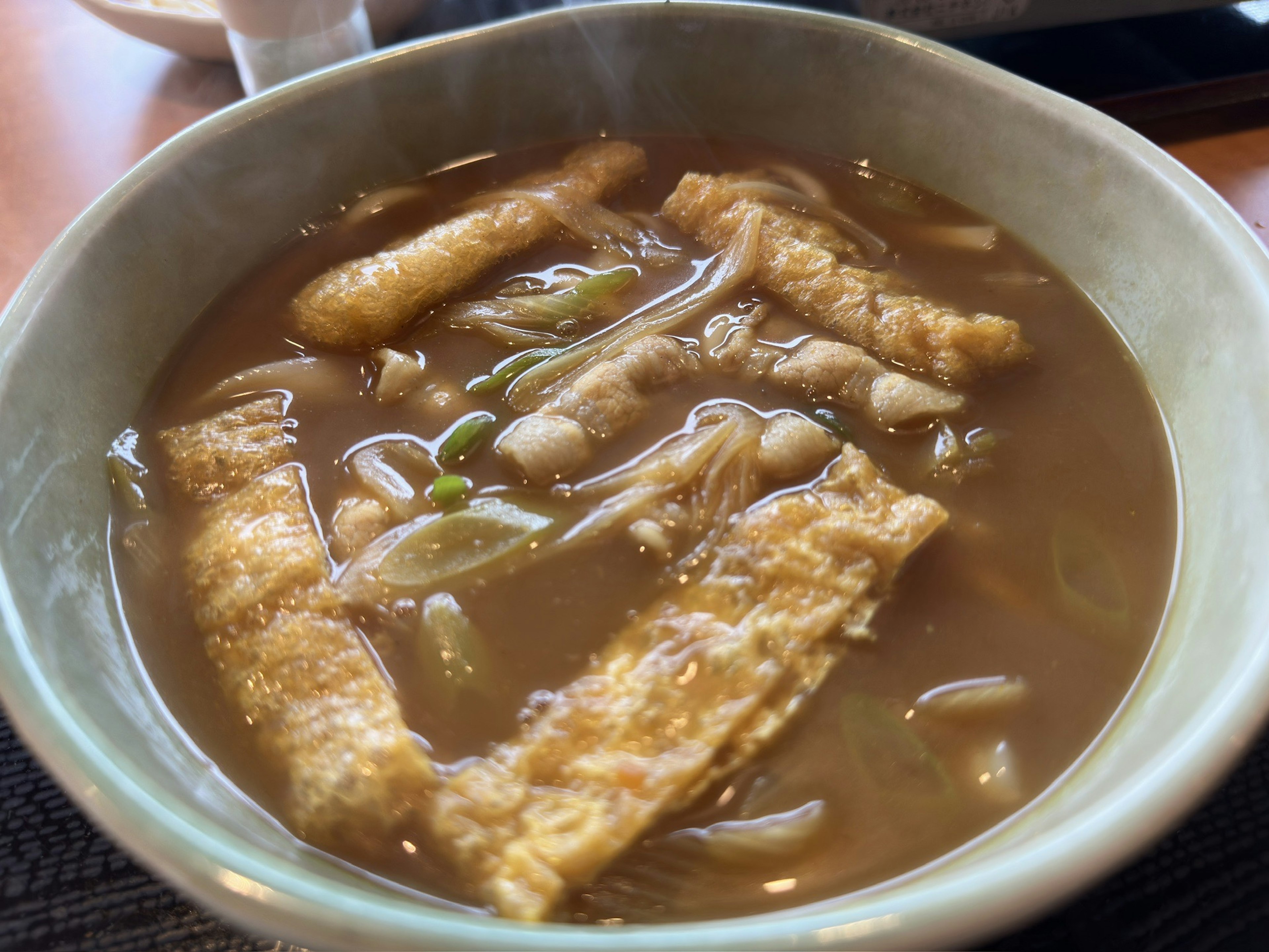 Un bol de soupe chaude avec des nouilles frites et des oignons verts