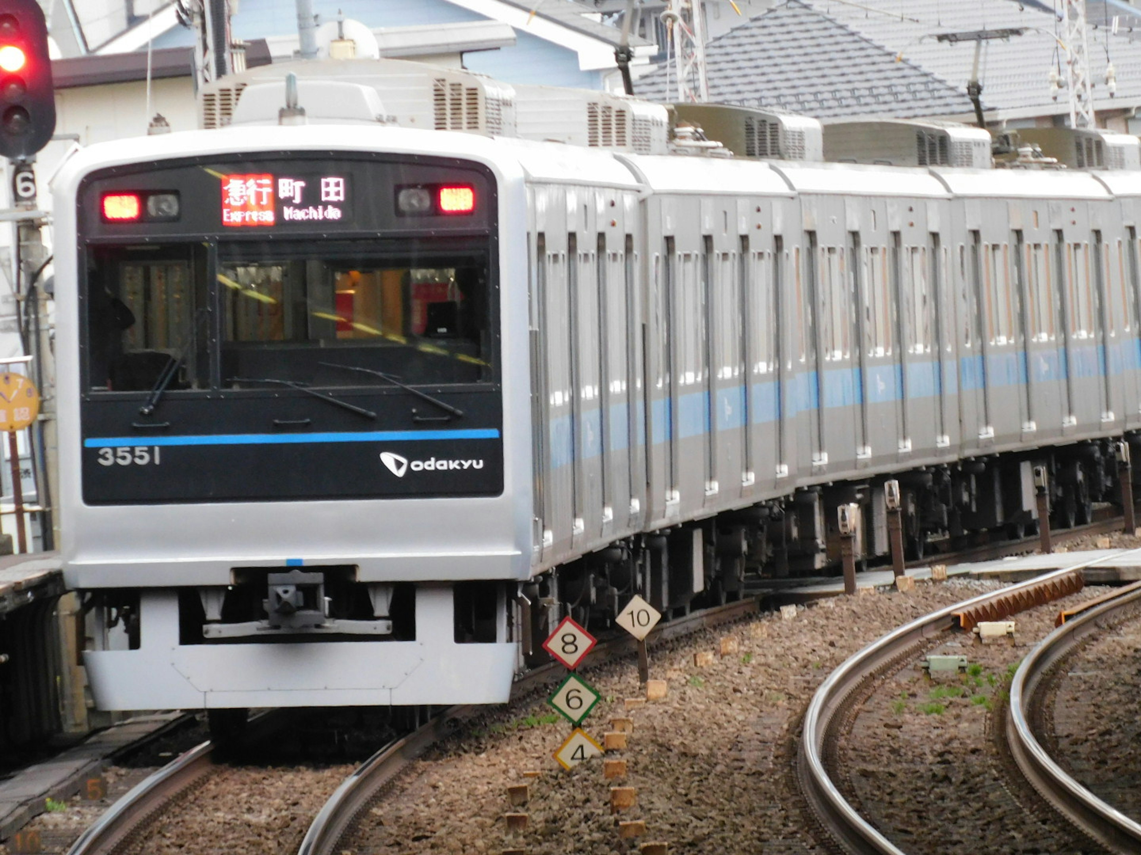 Train with blue stripe turning on curved tracks red signal light visible