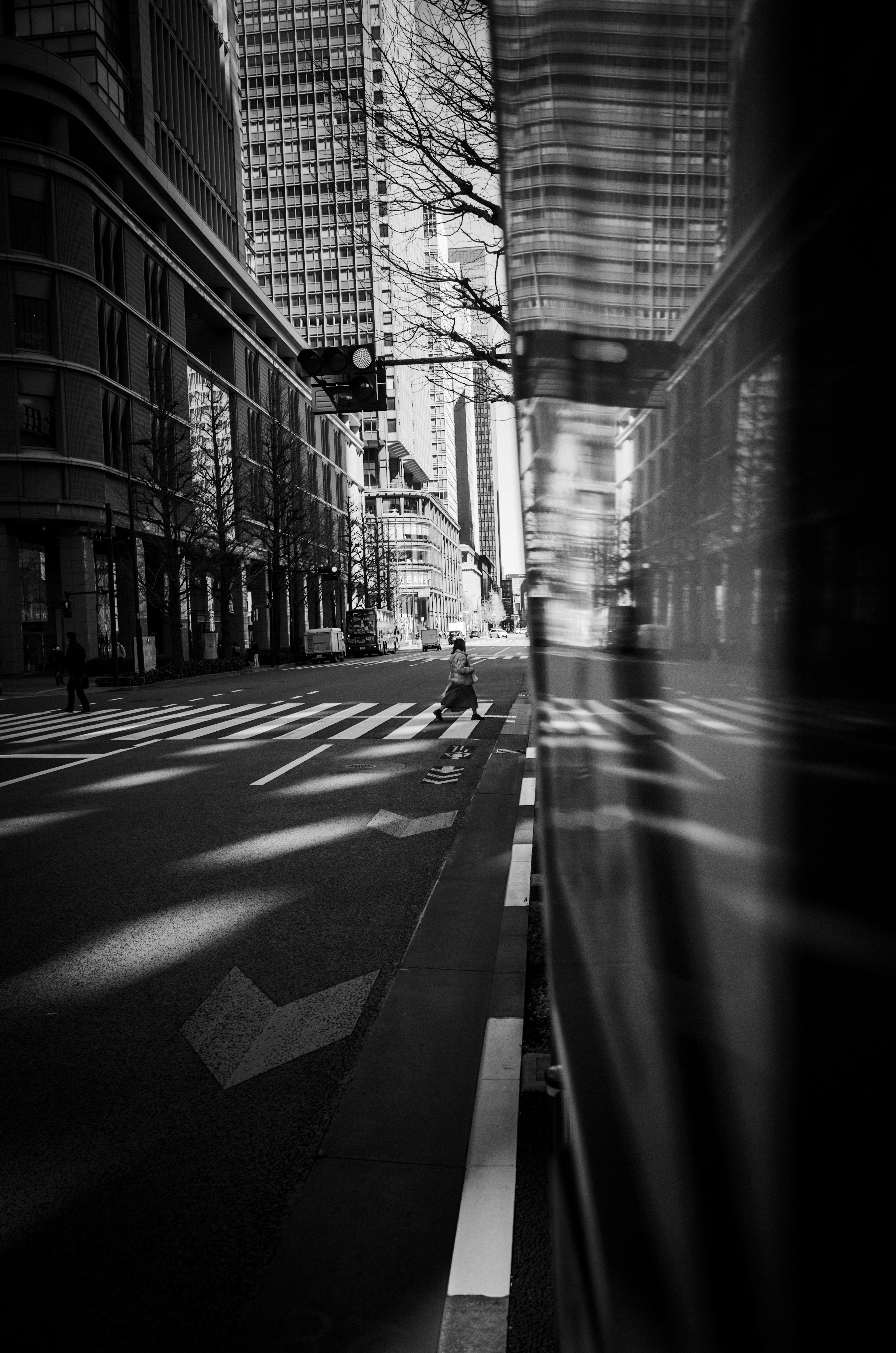 Black and white urban scene featuring a quiet street and reflections of skyscrapers