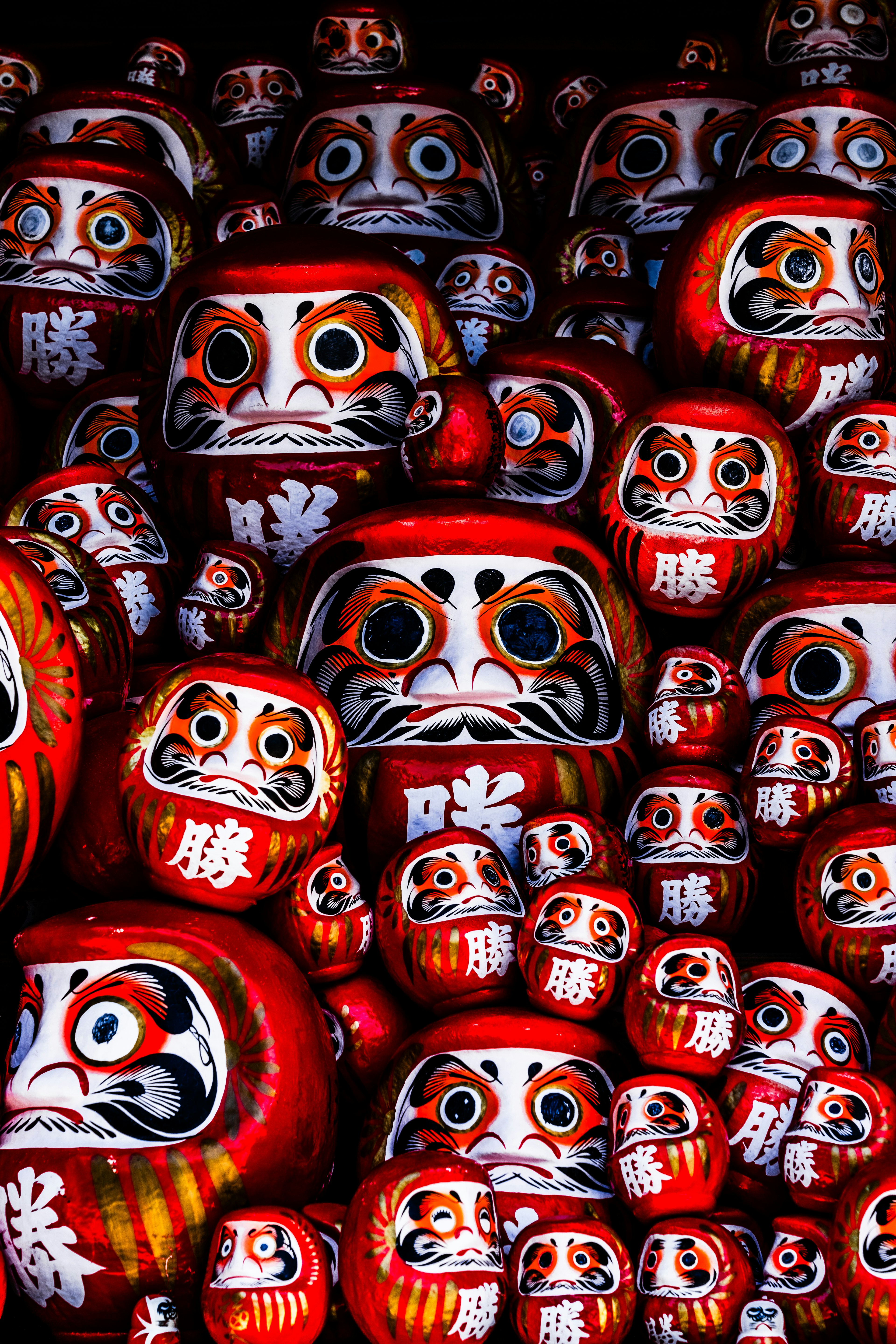 Una multitud de muñecas Daruma rojas con diversas expresiones faciales