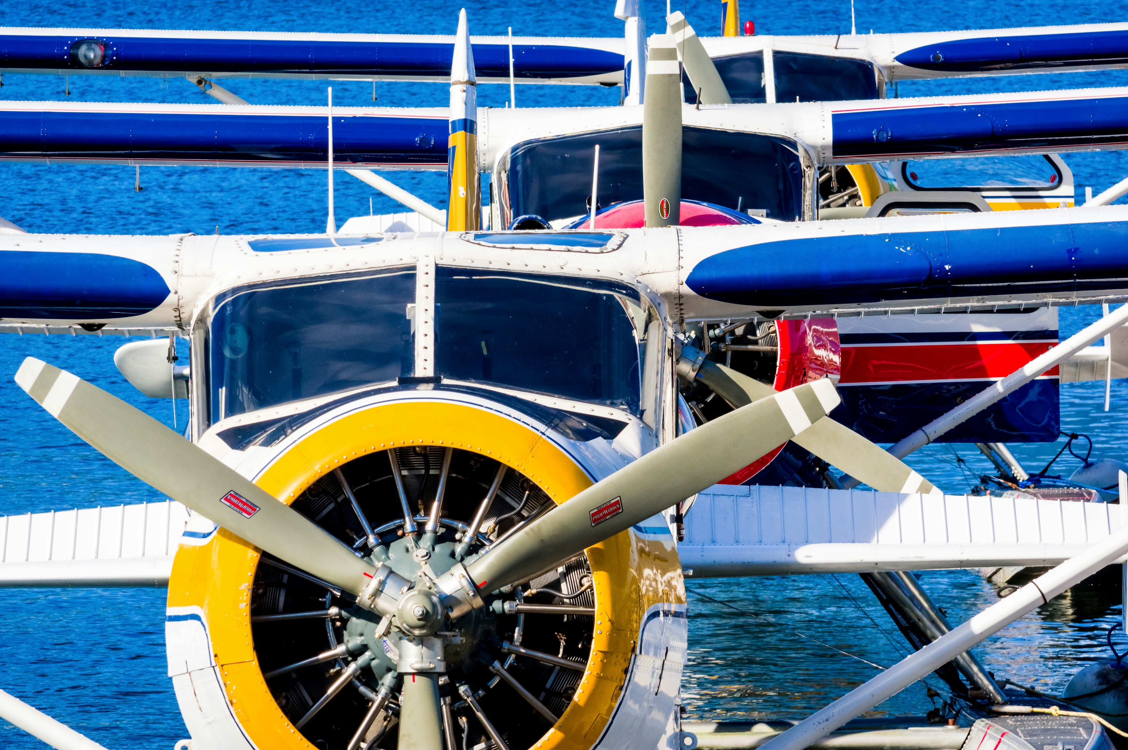 Primer plano de hidroaviones con hélices coloridas y fuselajes sobre agua azul