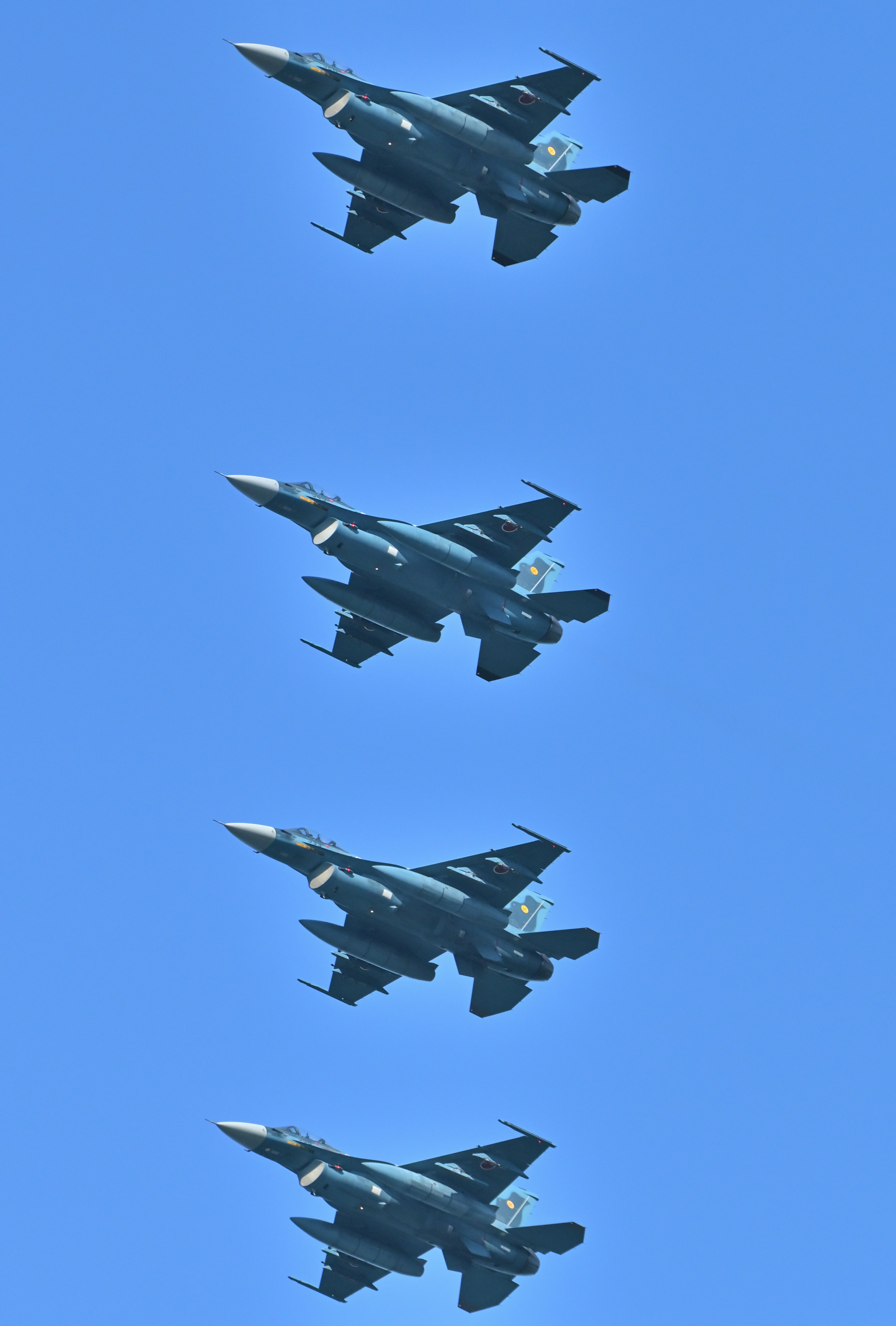 Formation flight of four fighter jets against a blue sky