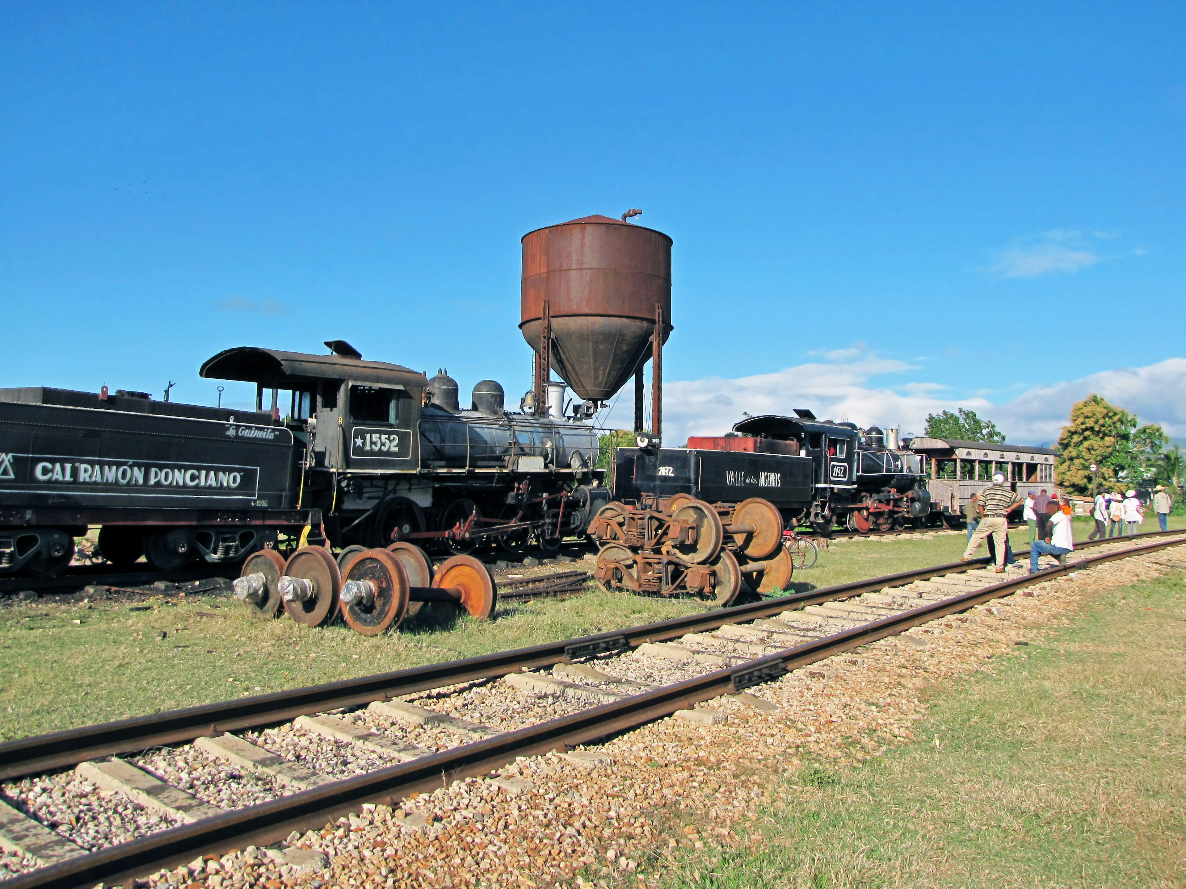 Storiche locomotive a vapore e carrozze ferroviarie lungo i binari con un serbatoio d'acqua vintage sullo sfondo