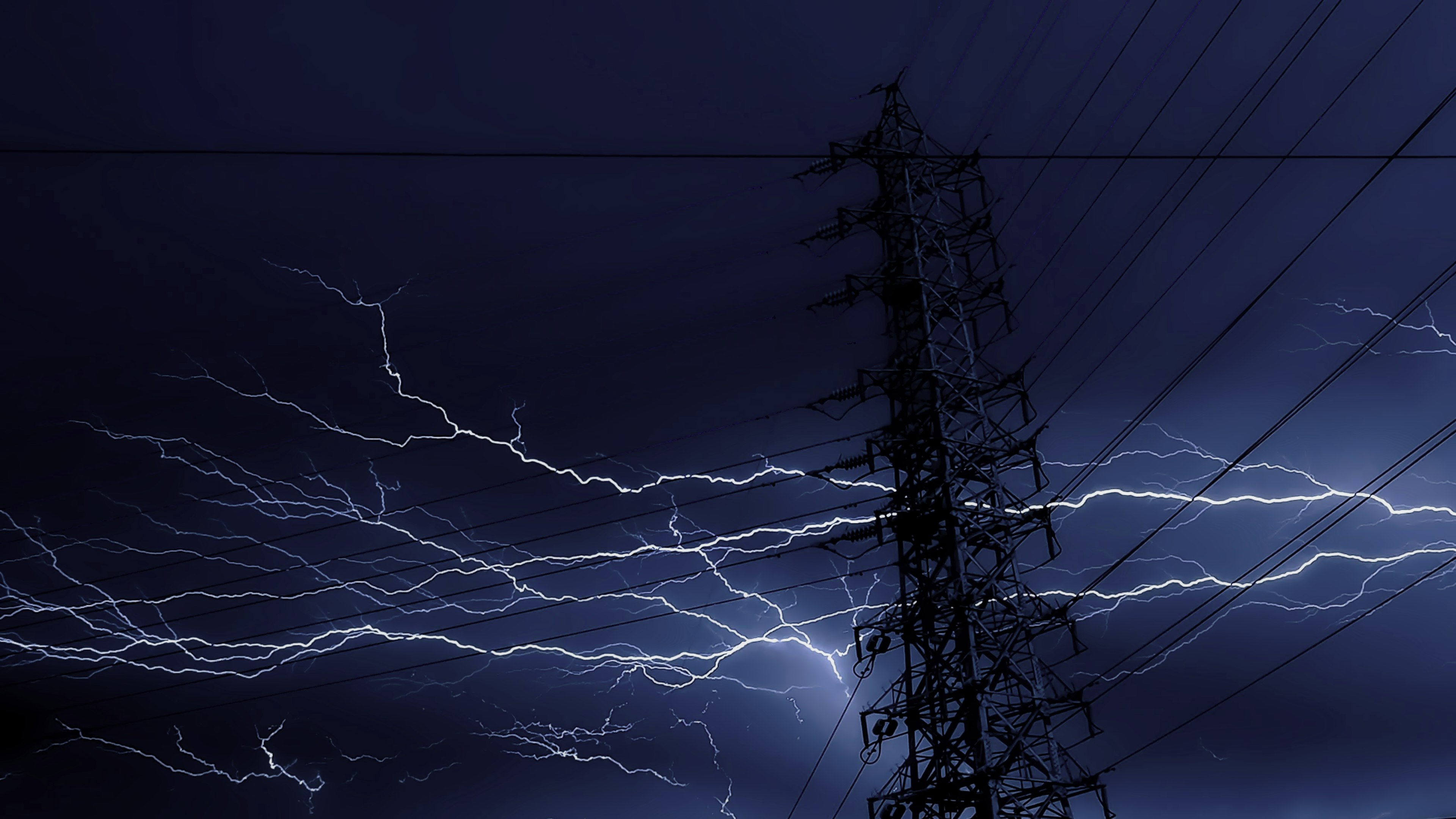 Lightning striking in a dark sky with a power pole