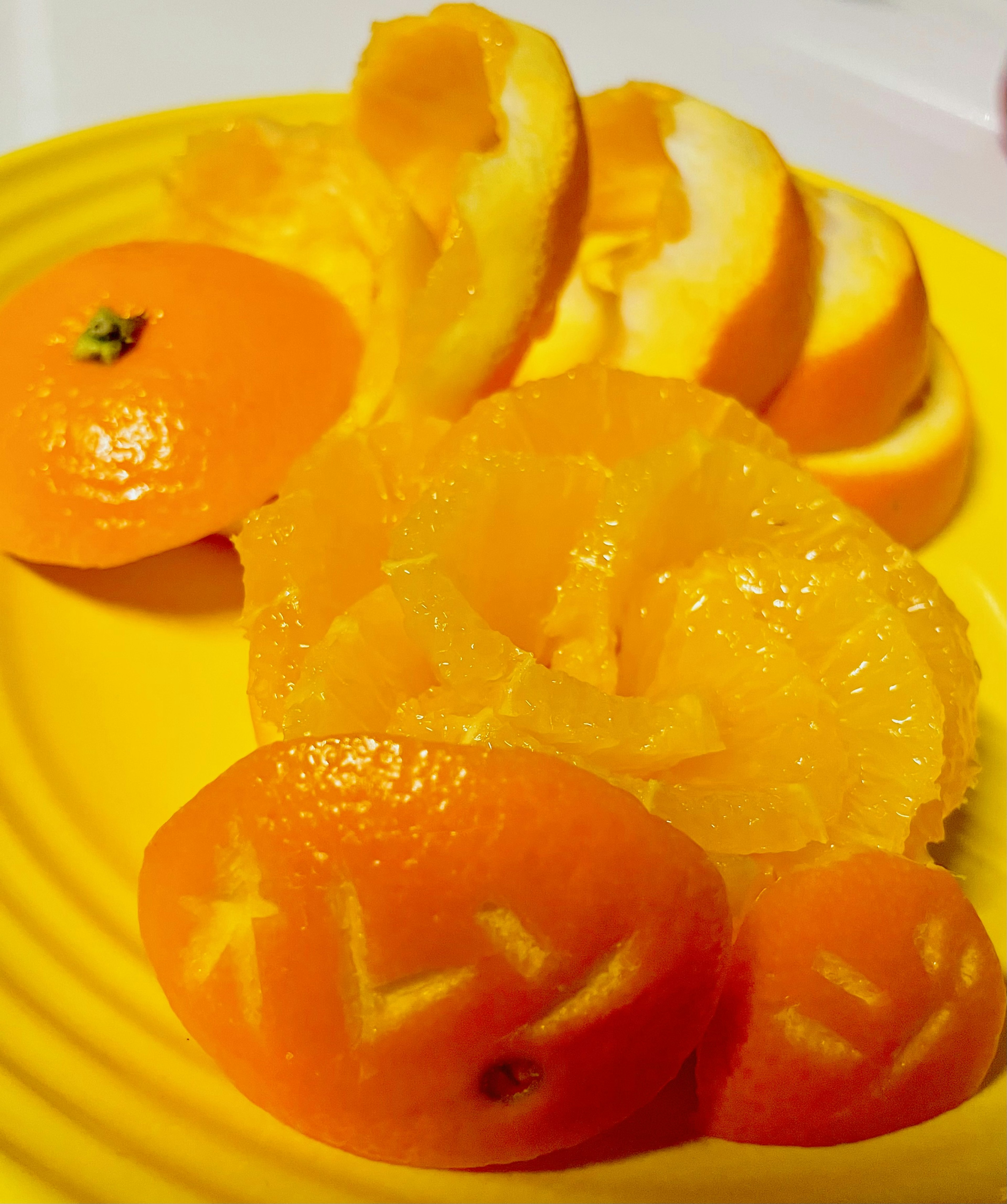 Vibrant oranges and their peels arranged on a yellow plate