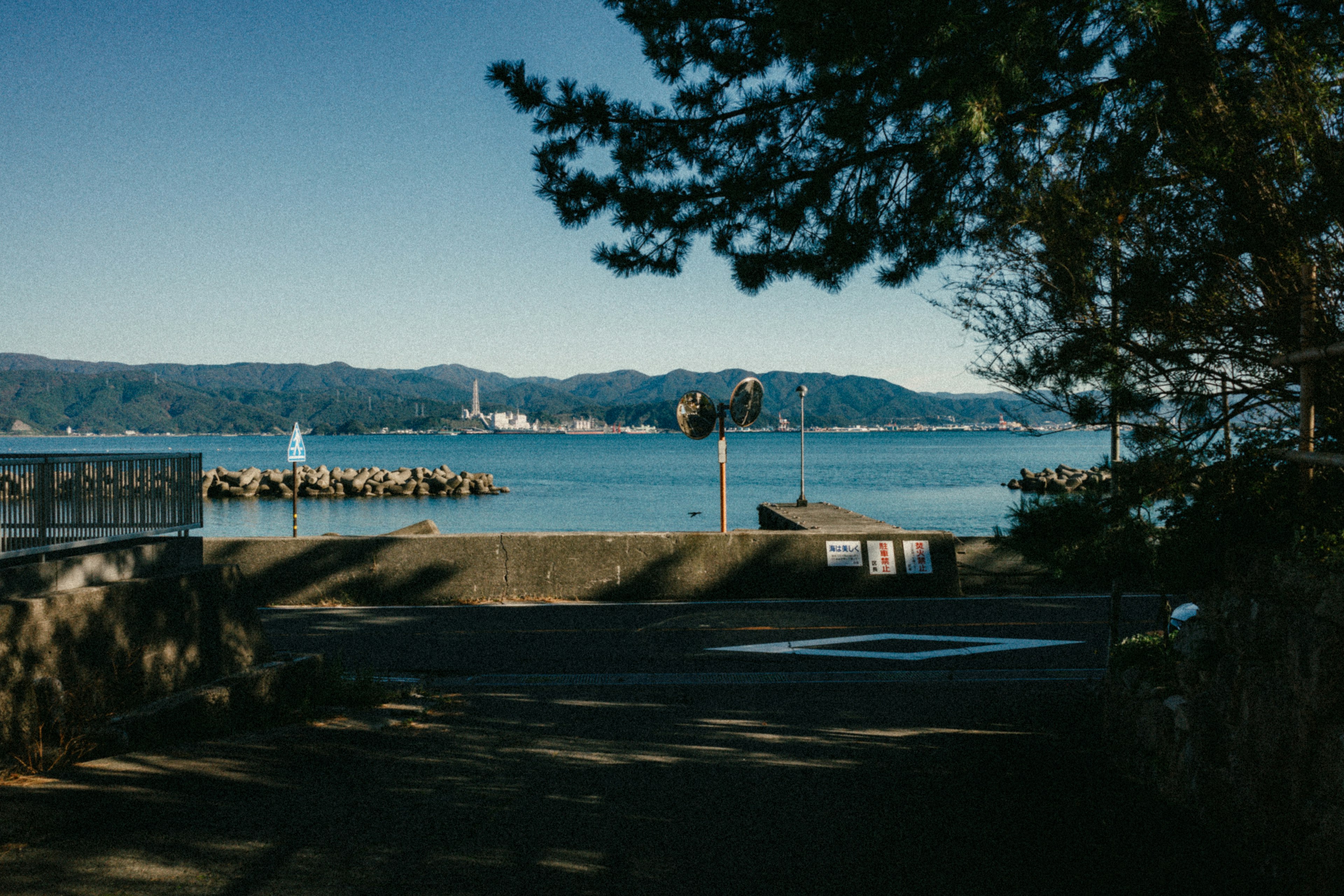 Scenic view of blue sea and mountains with a small sailboat on calm waters