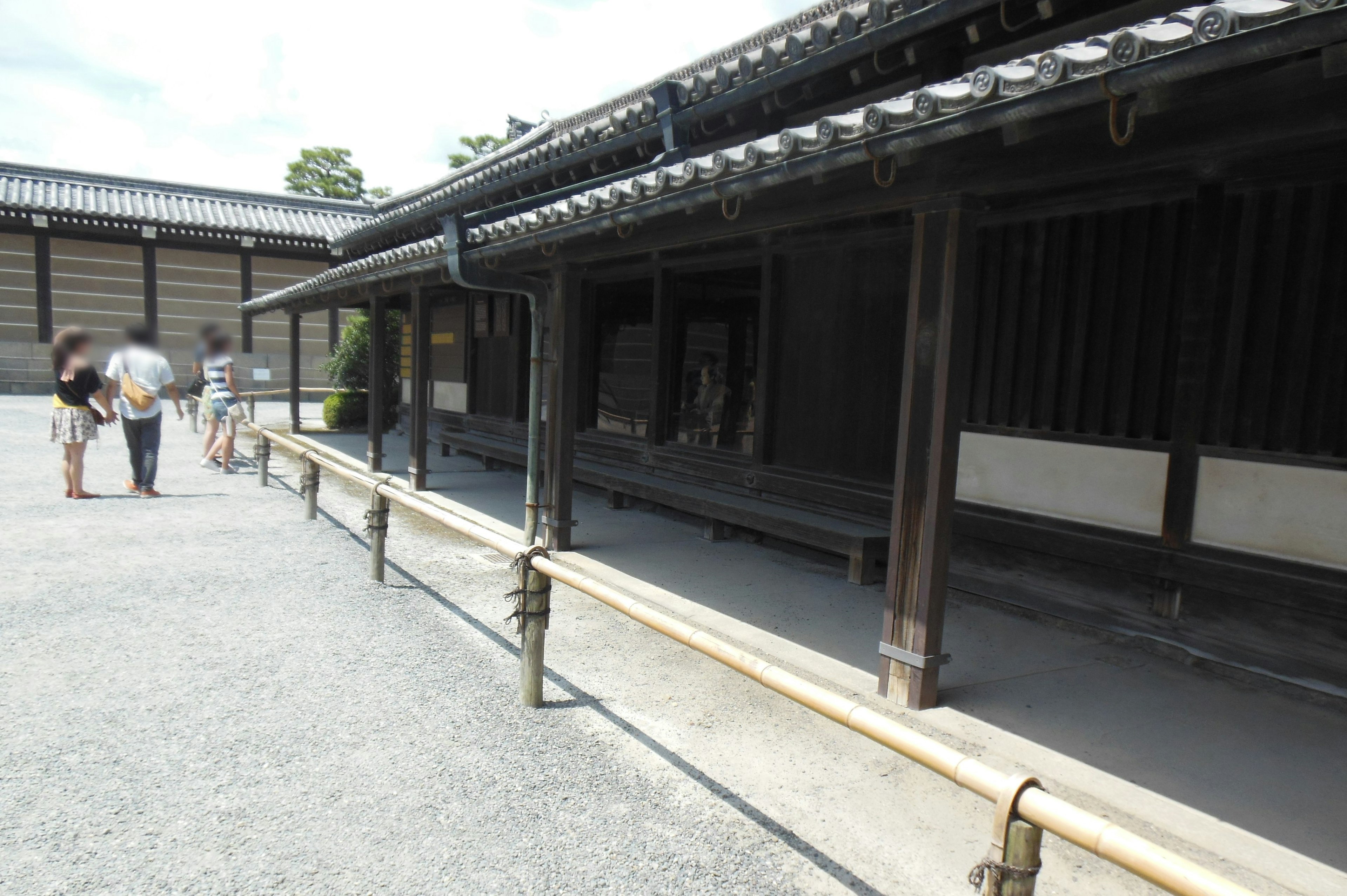 Besucher gehen entlang eines Steinwegs neben einem traditionellen japanischen Gebäude