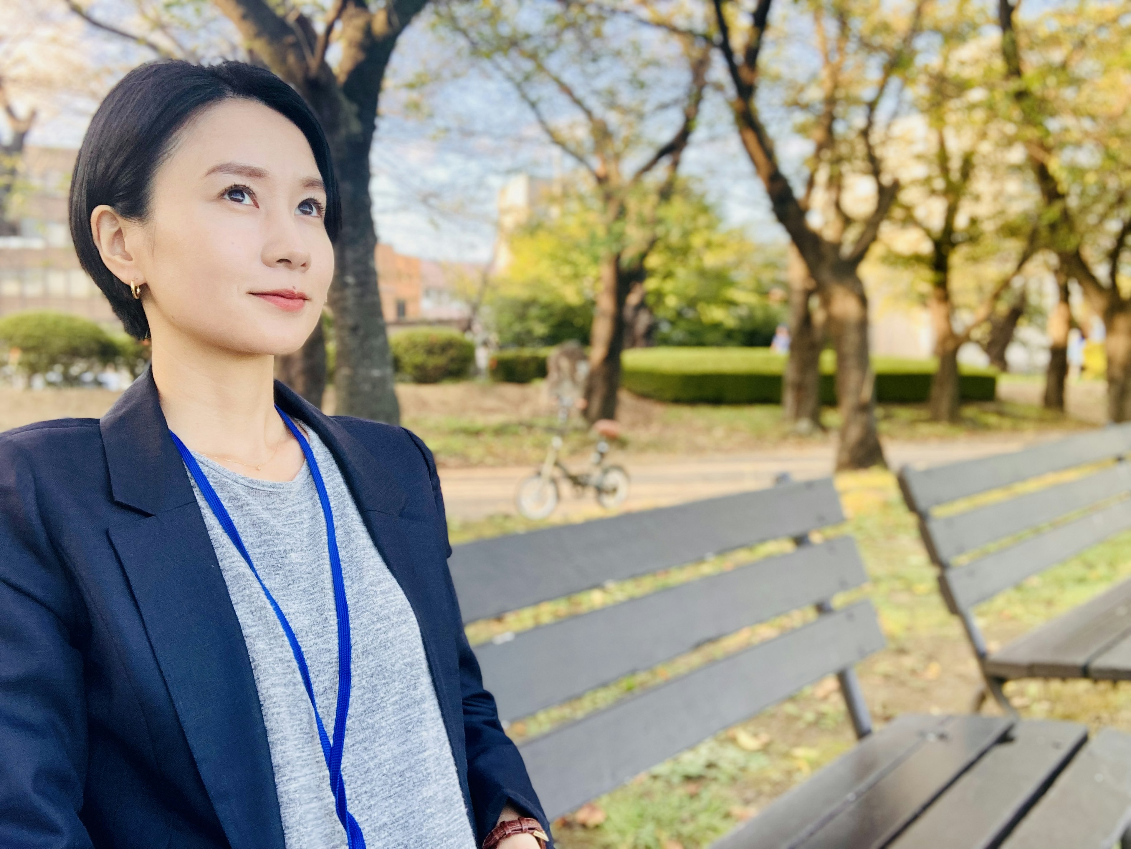 A woman in business casual attire sitting on a park bench