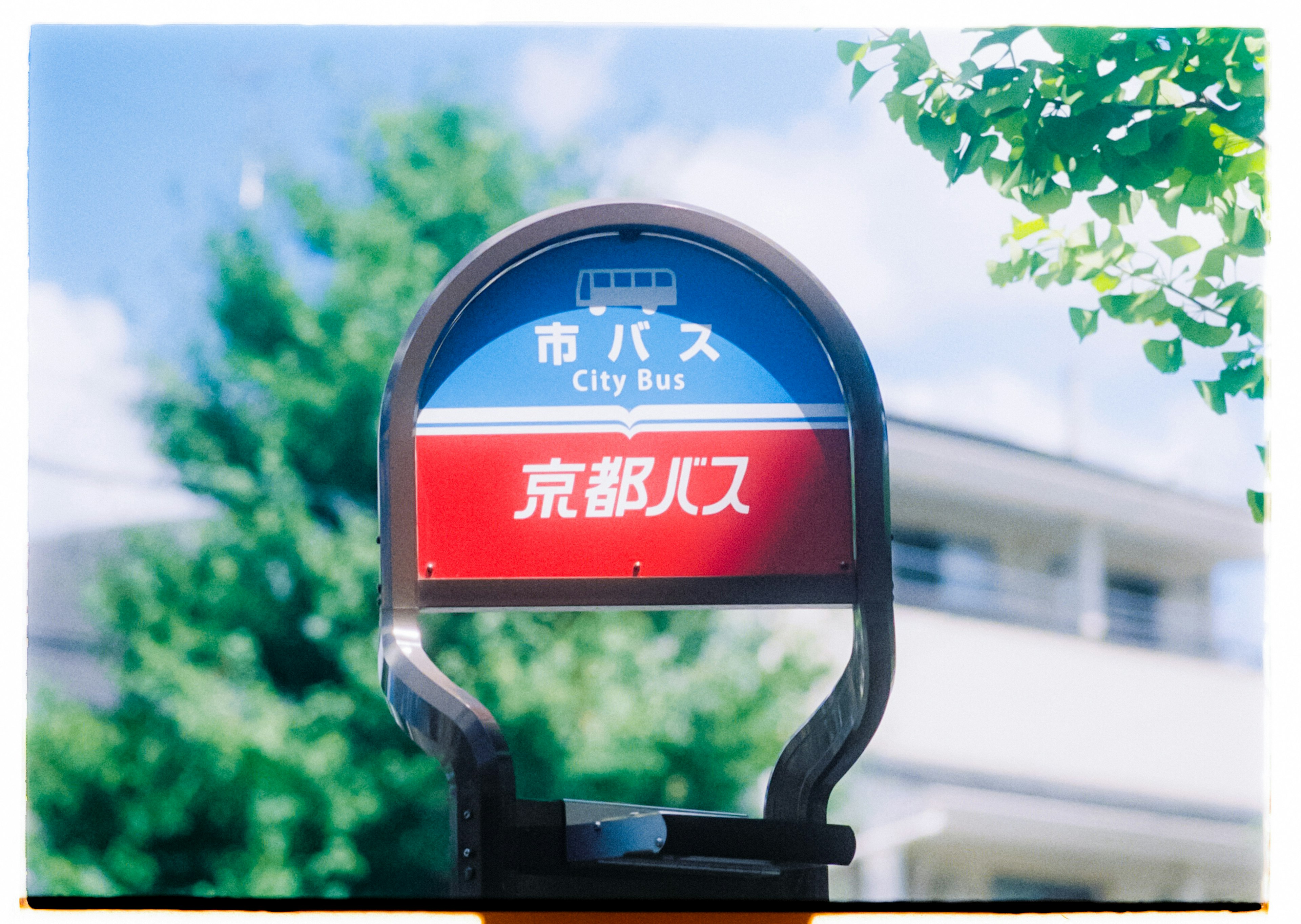 Bus stop sign under blue sky featuring Kyoto bound in prominent red lettering