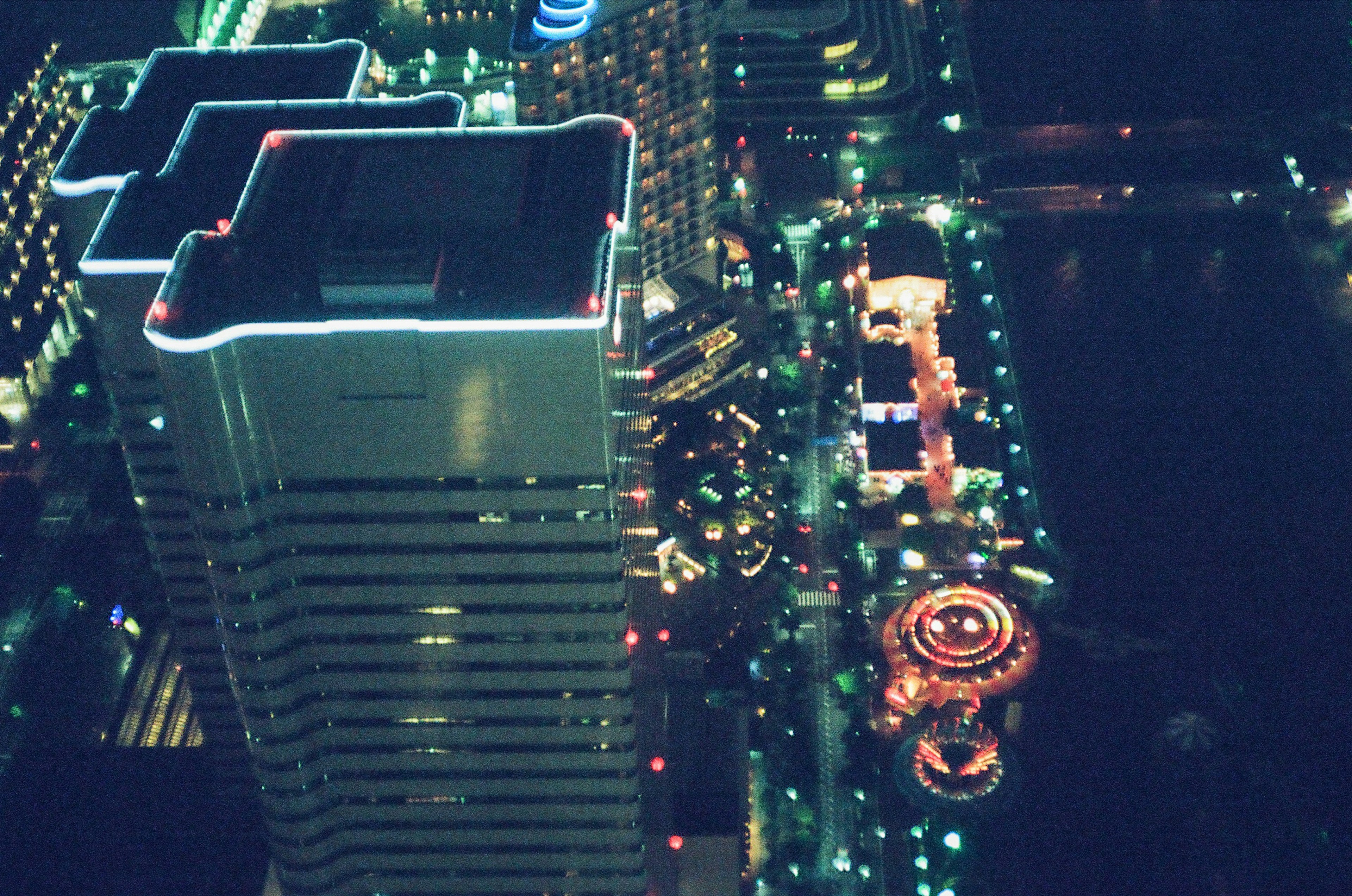 Night cityscape featuring a high-rise building and a carnival ferris wheel