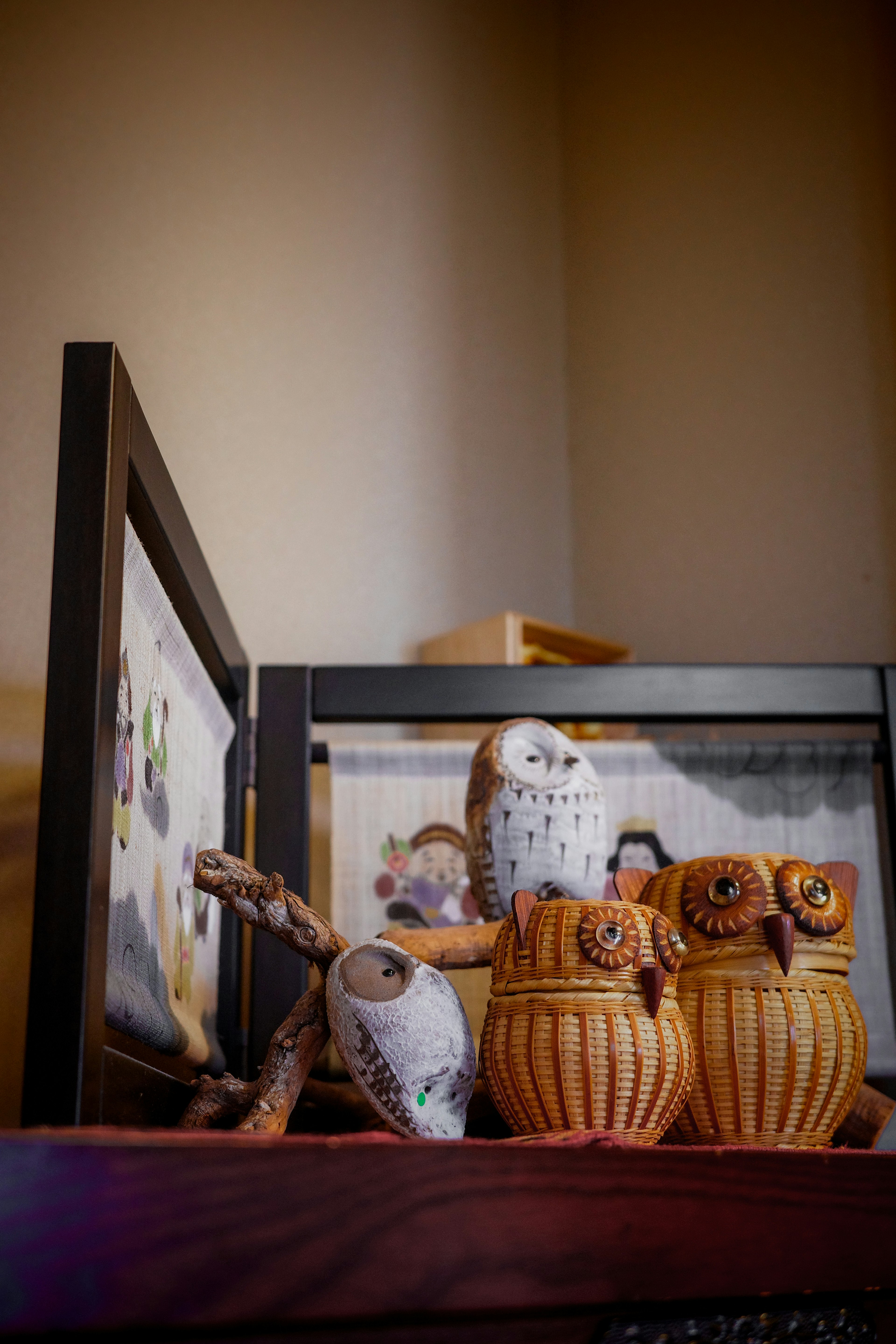 Esculturas de búhos de madera dispuestas en una estantería con una imagen enmarcada al fondo