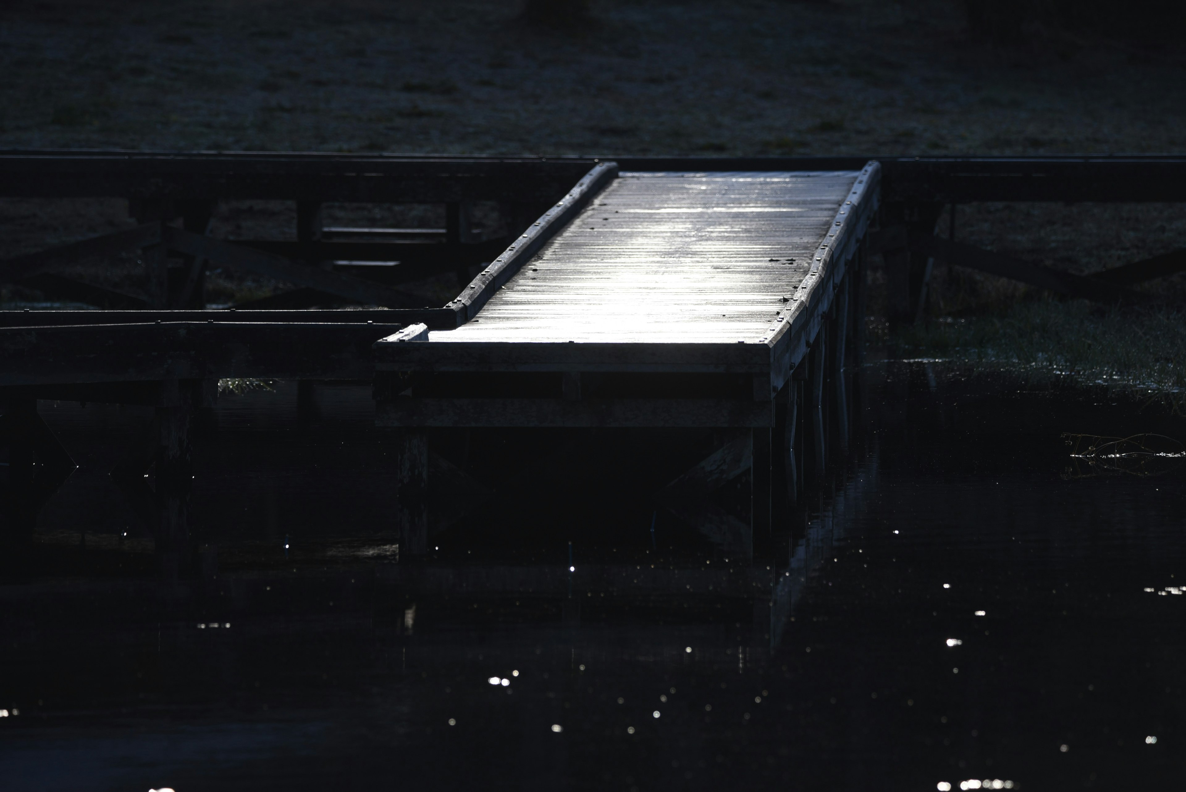 Holzsteg, der schwaches Licht auf der Wasseroberfläche reflektiert