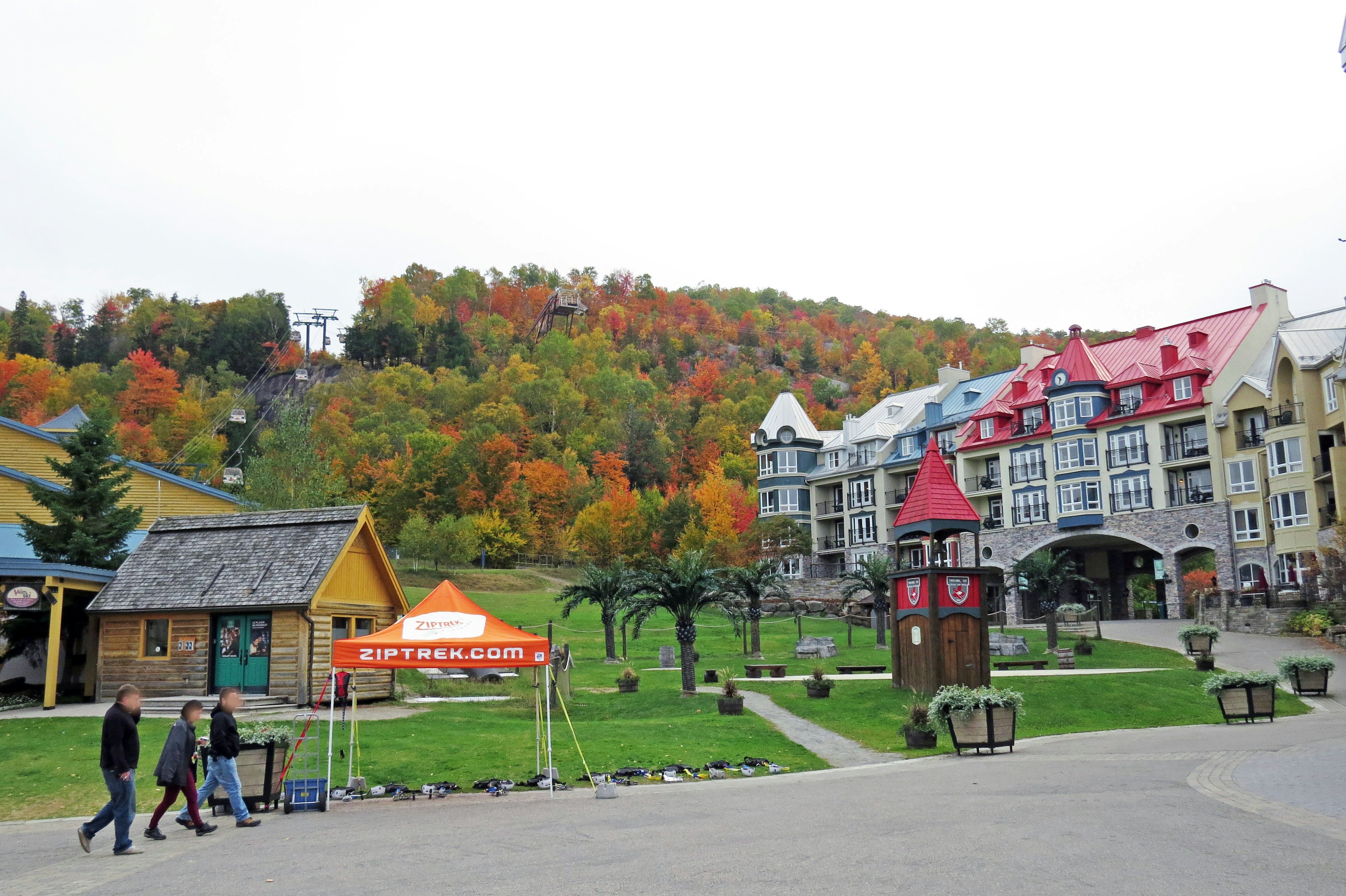 Malersicher Blick auf eine Stadt mit bunten Gebäuden und einer lebhaften Herbstlandschaft im Hintergrund Menschen, die gehen