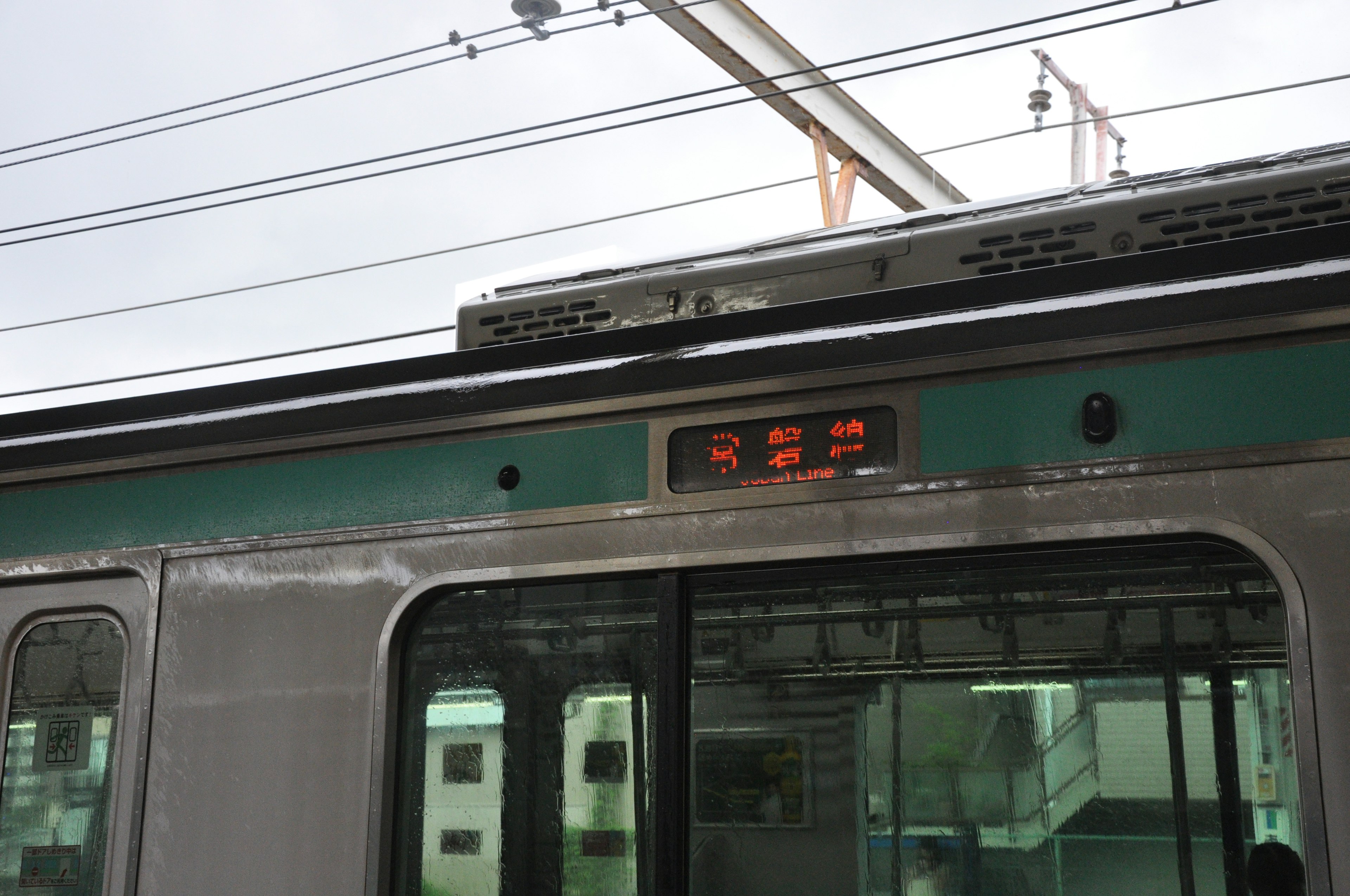 電車の上部にあるデジタル表示が見える駅の風景