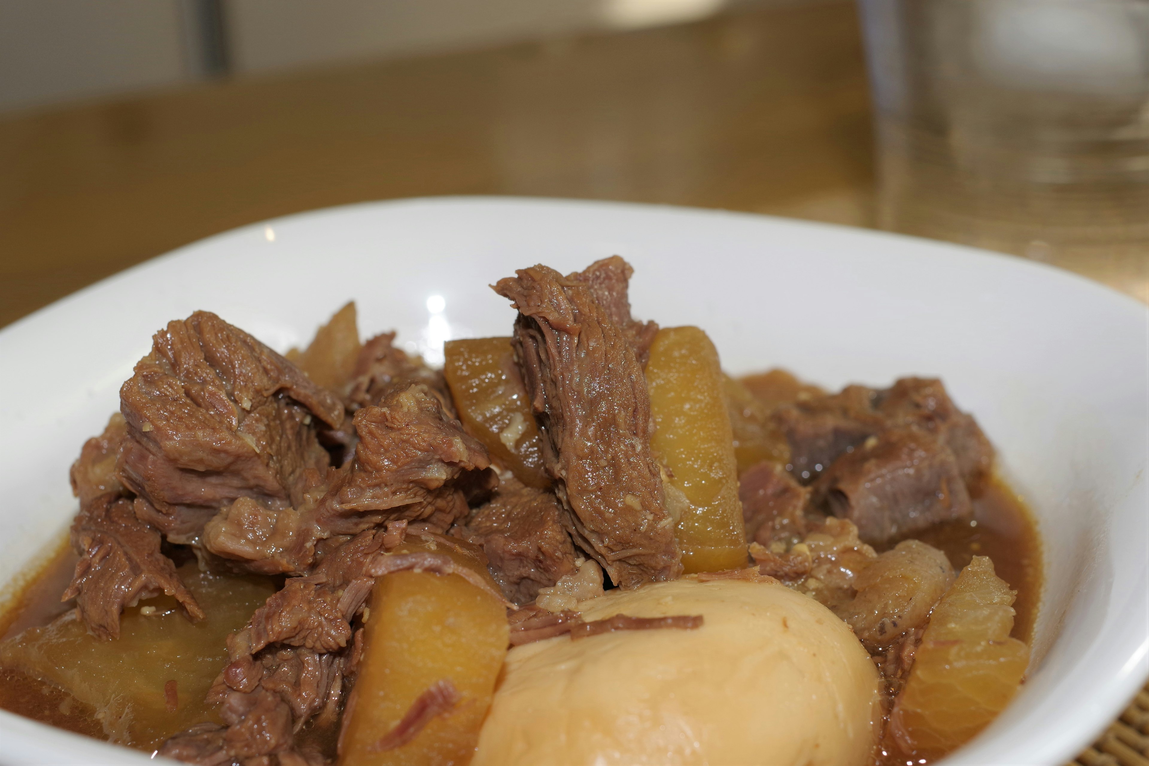 A white bowl filled with beef and vegetable stew featuring chunks of meat and potatoes