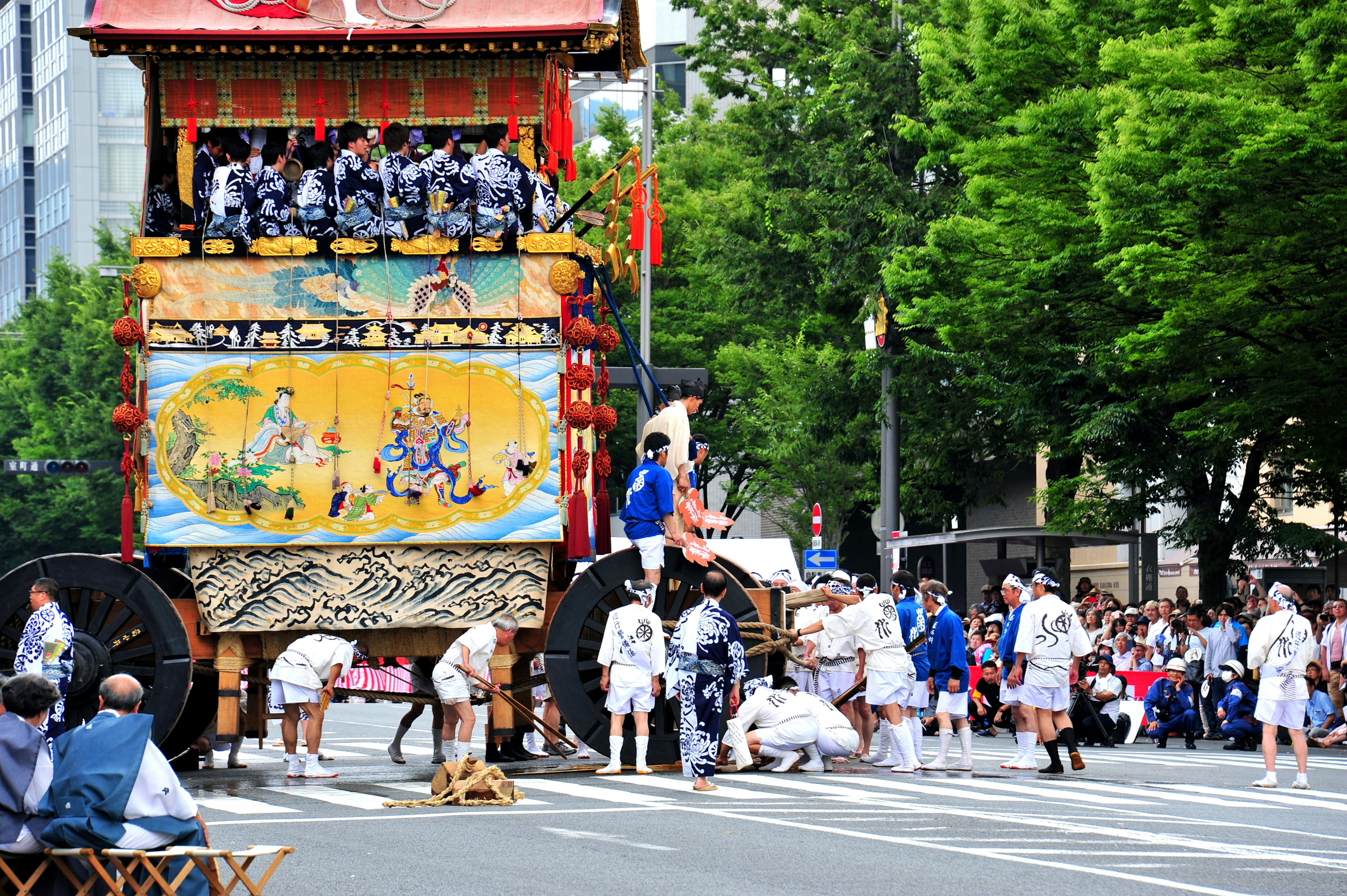 Carro de festival moviéndose por la calle con personas en trajes tradicionales reunidas alrededor