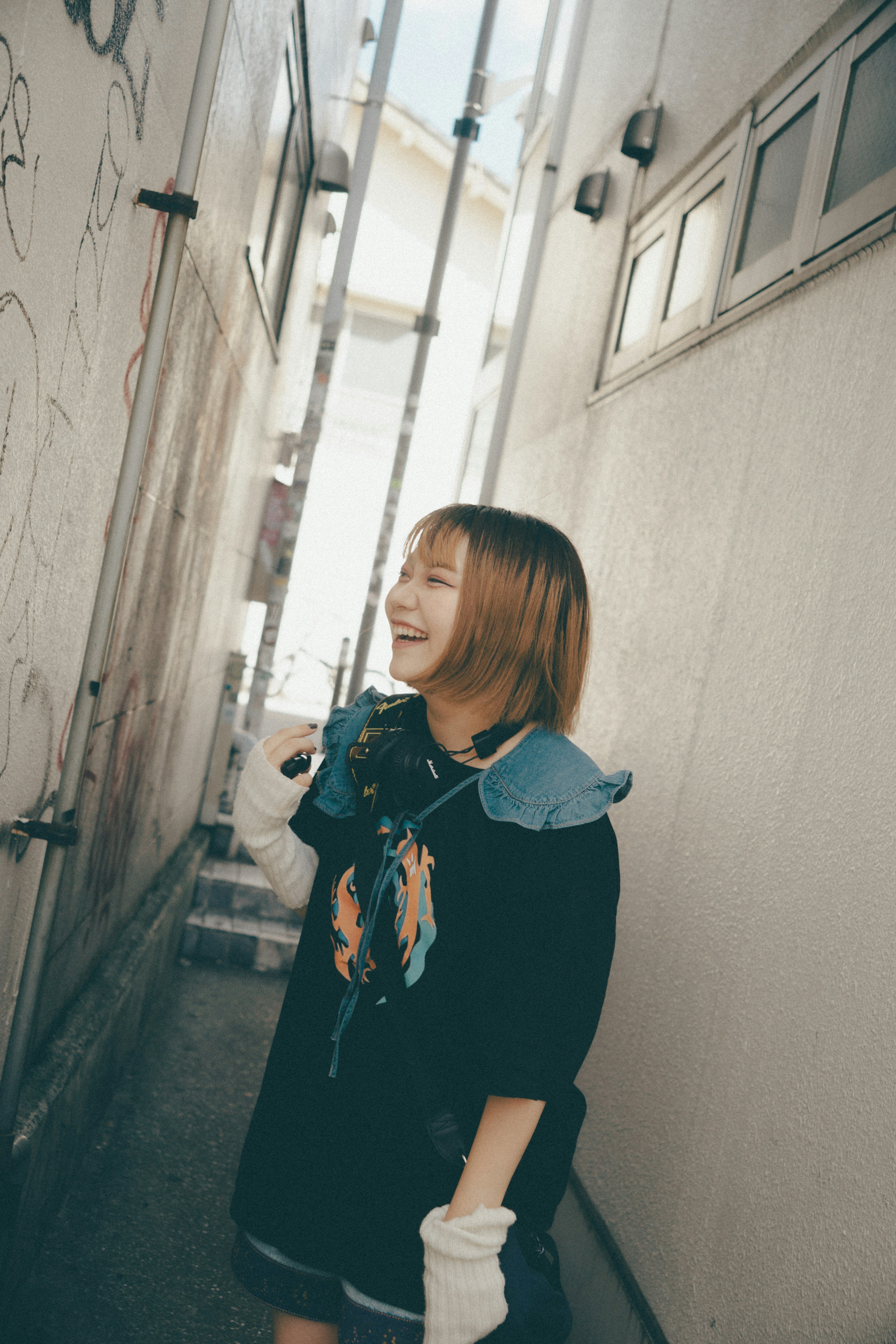 A smiling woman standing in a narrow alley