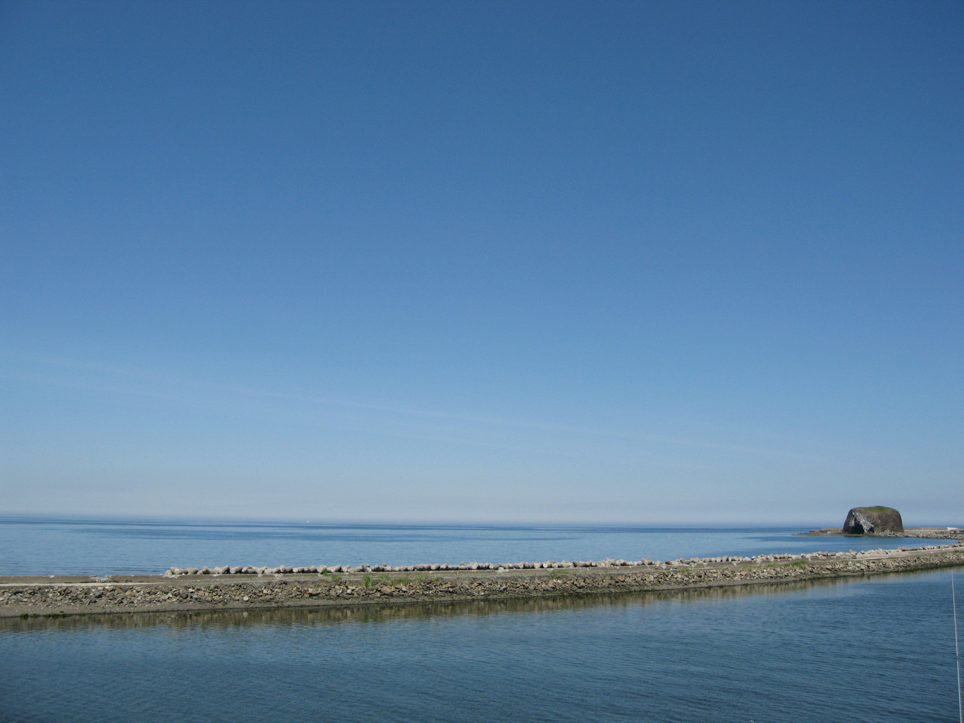 Eine ruhige Landschaft mit klarem blauen Himmel und ruhigem Meer mit einer kleinen Hütte