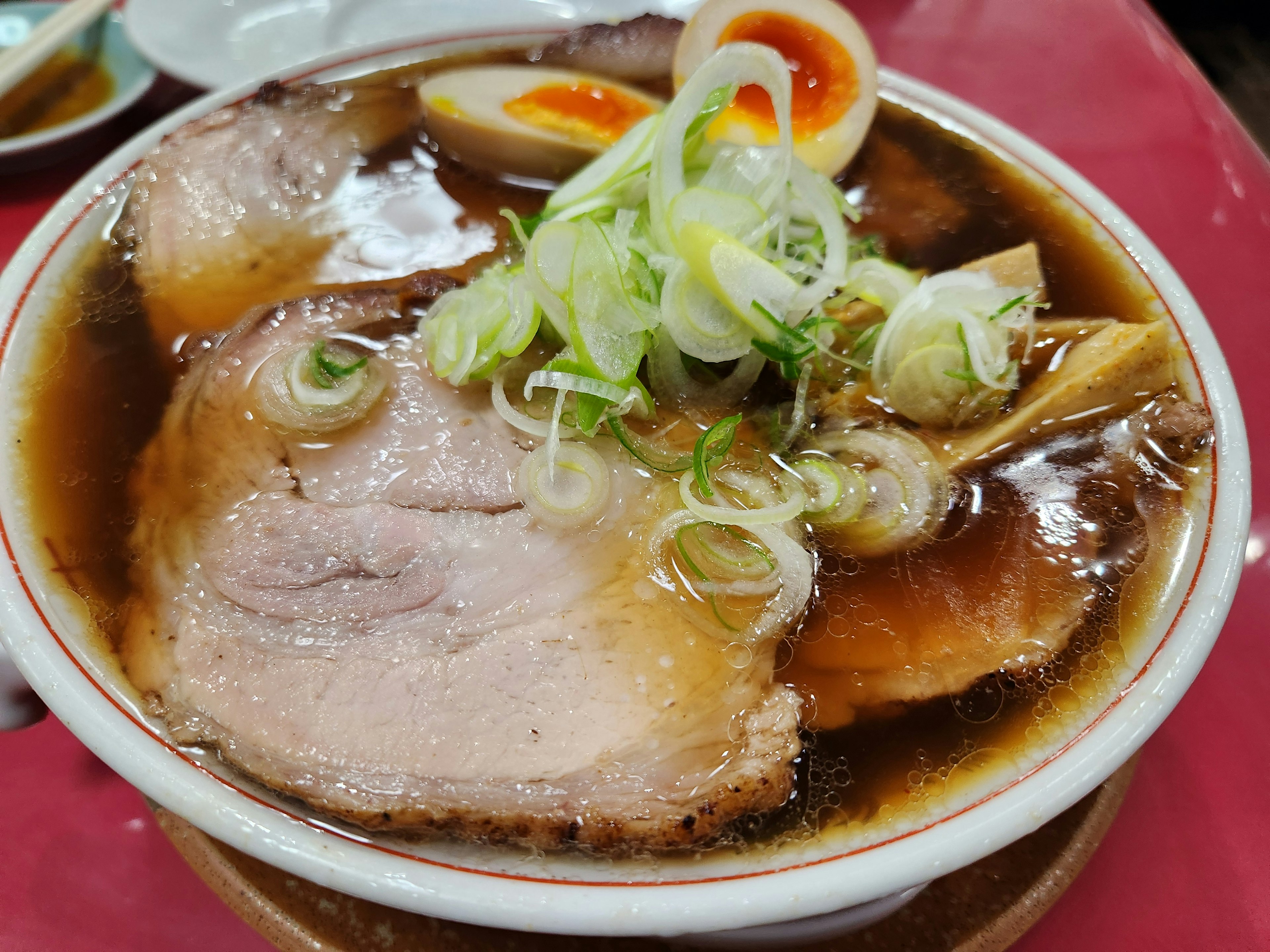 Mangkuk ramen dengan chashu, bawang hijau, dan telur setengah matang