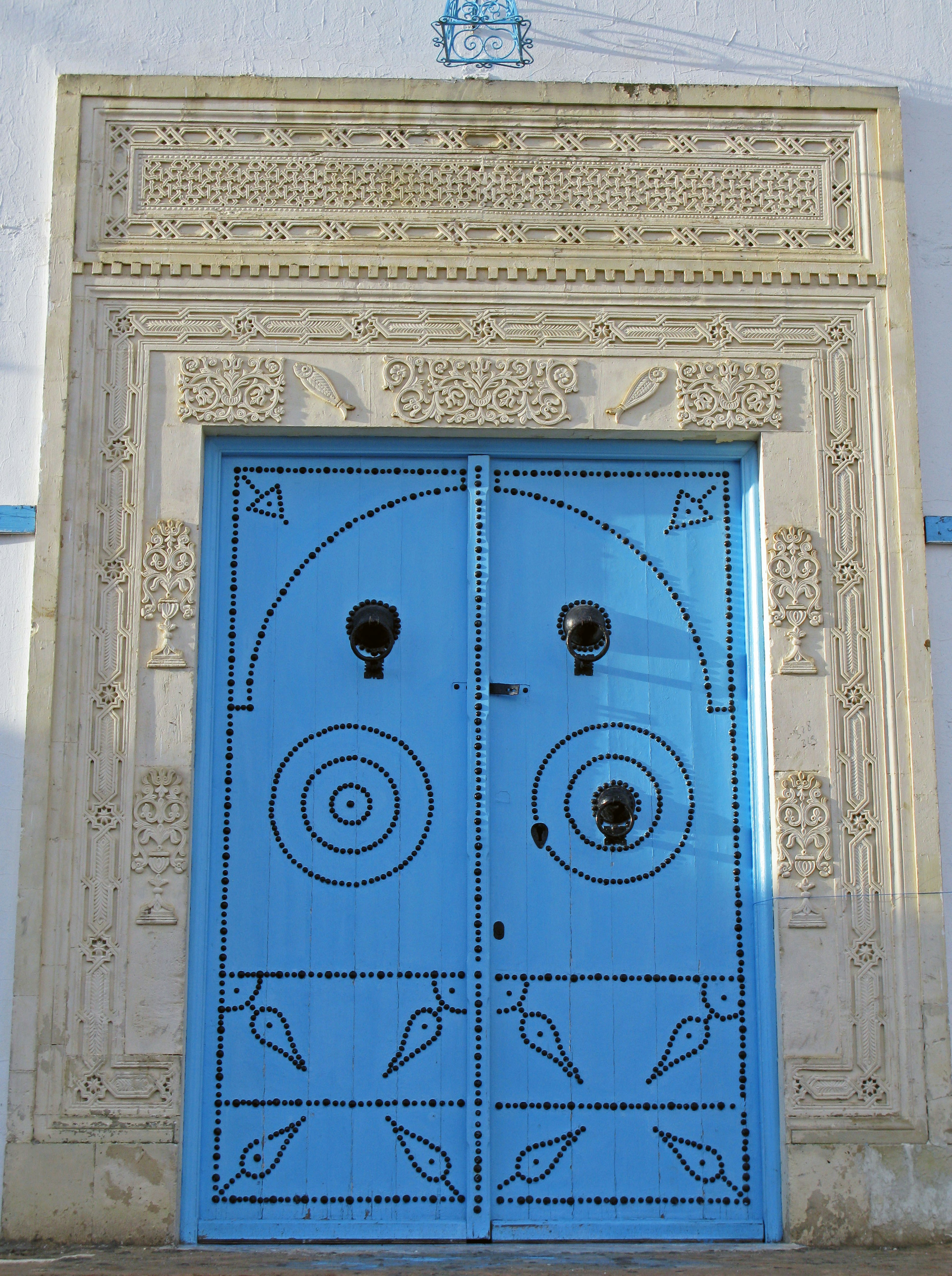 Porte bleue décorative avec des sculptures et mur blanc