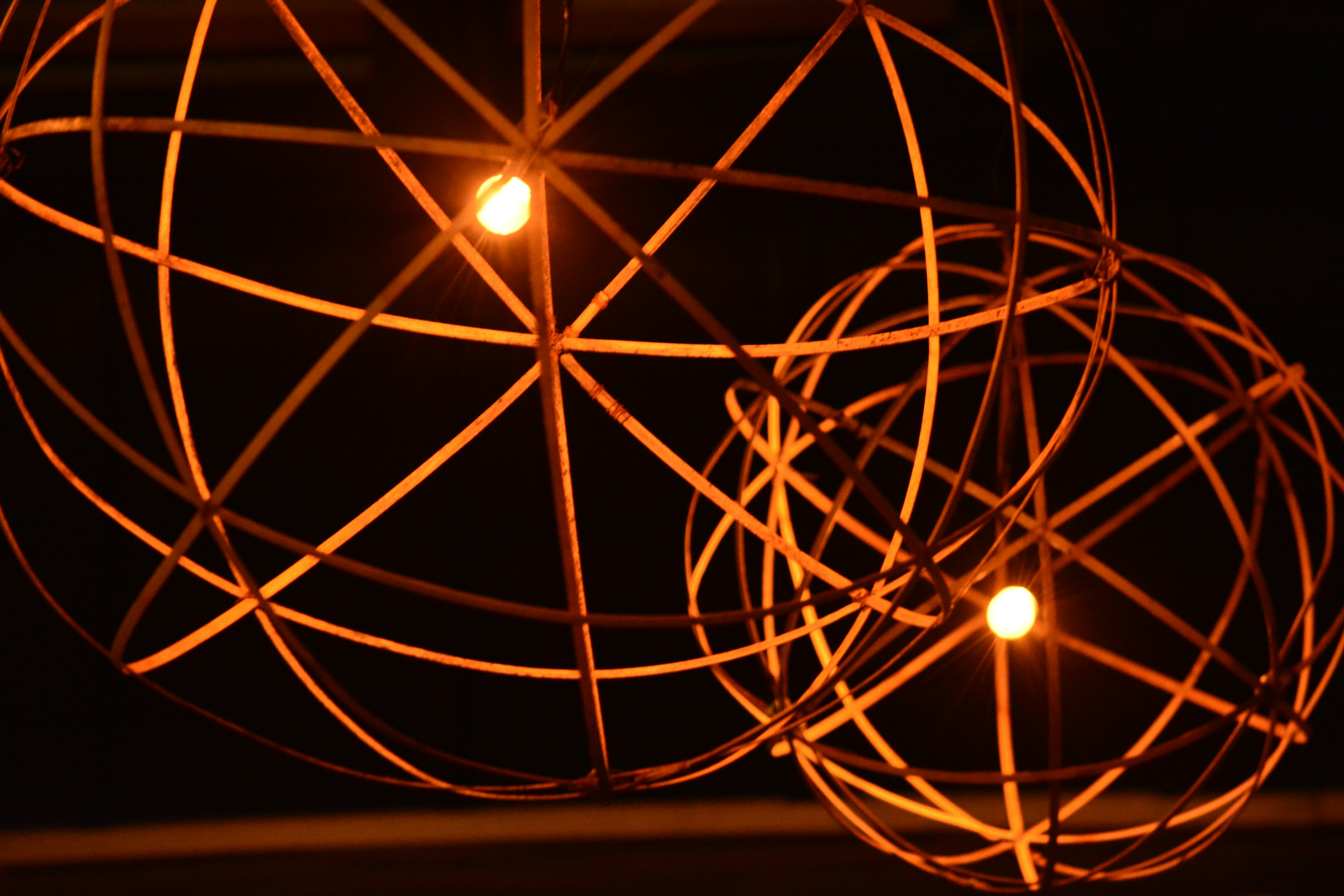 Photo of a lighting fixture design featuring metal spherical shades with warm lights glowing inside