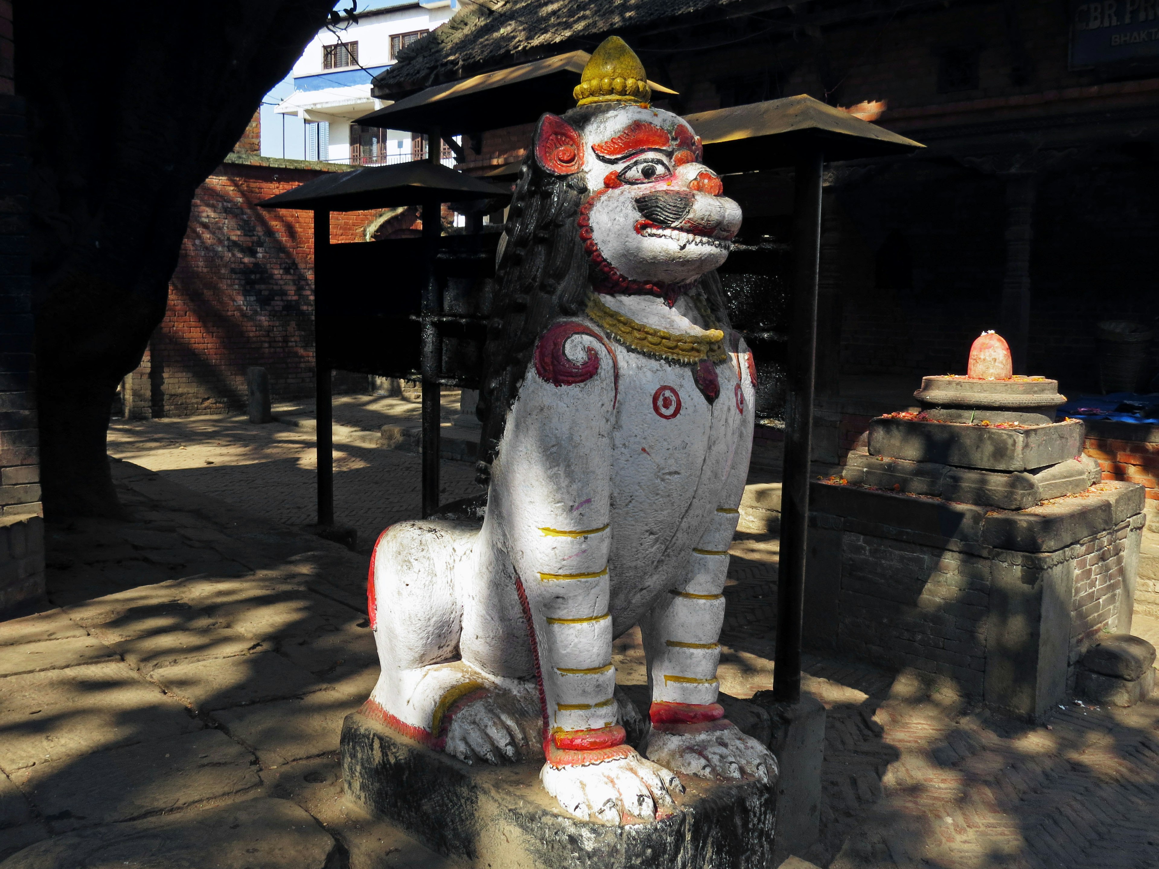 White lion statue with a yellow hat surrounded by shadows