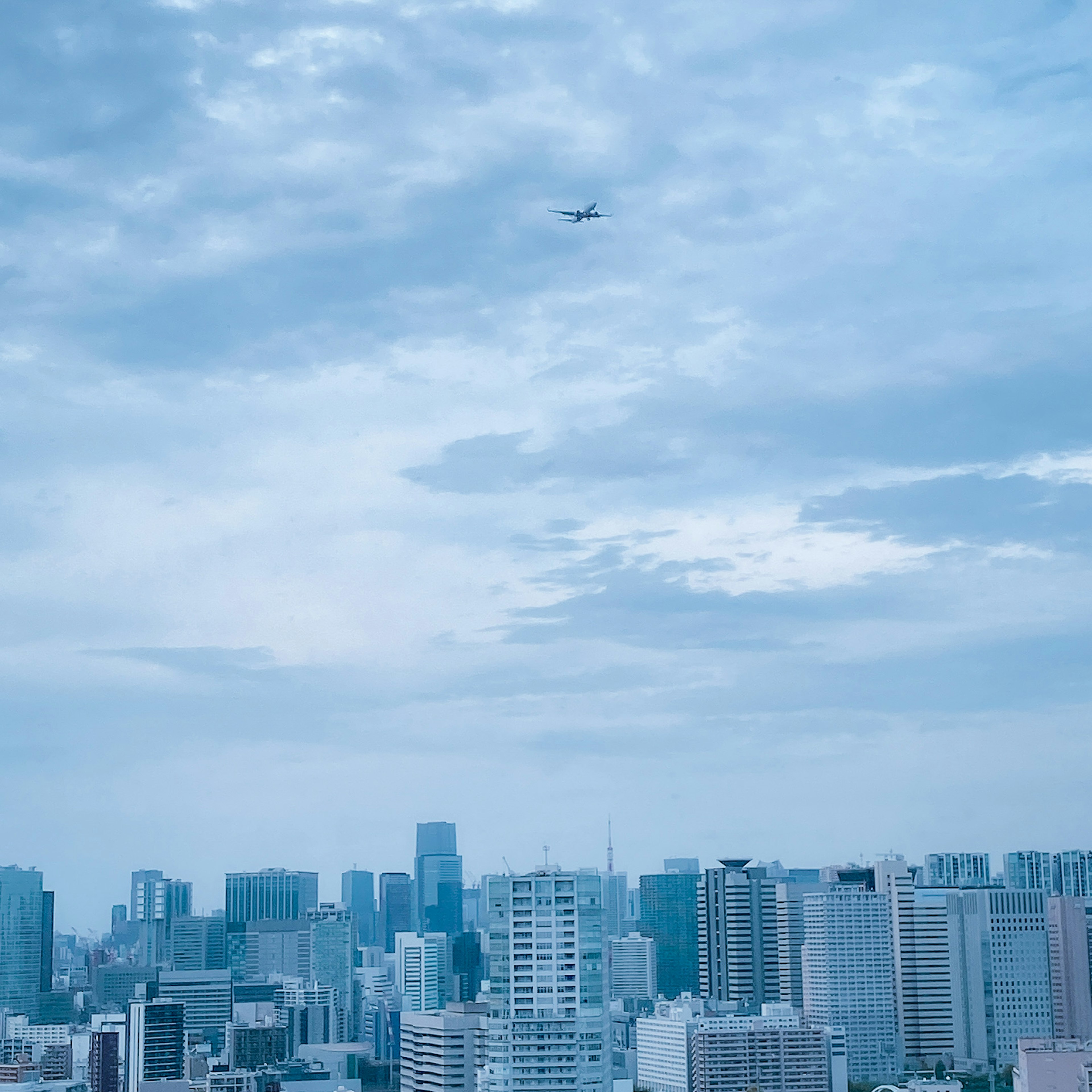 Paisaje urbano con edificios y un avión en el cielo azul