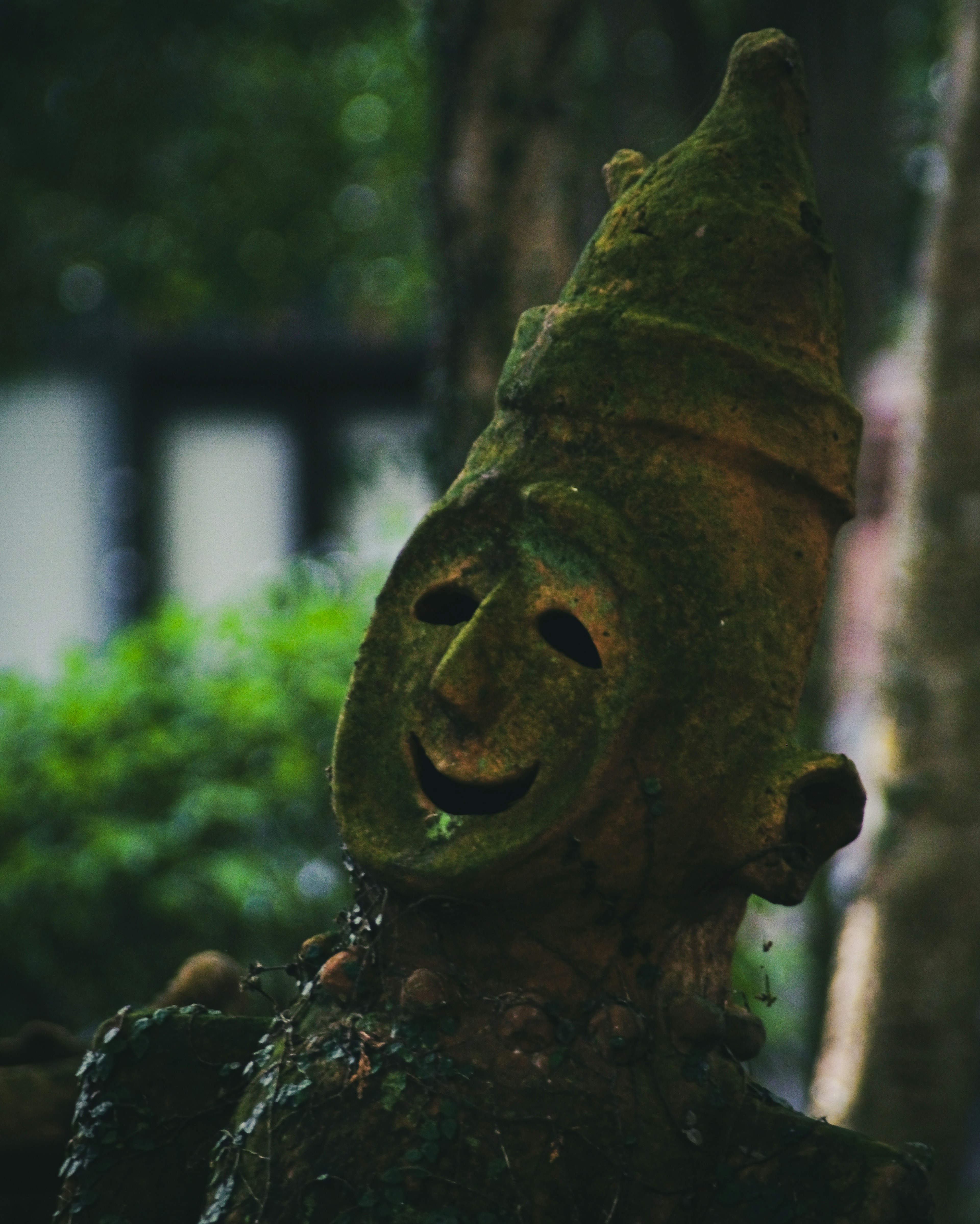 Escultura antigua que muestra un rostro sonriente sobre un fondo verde