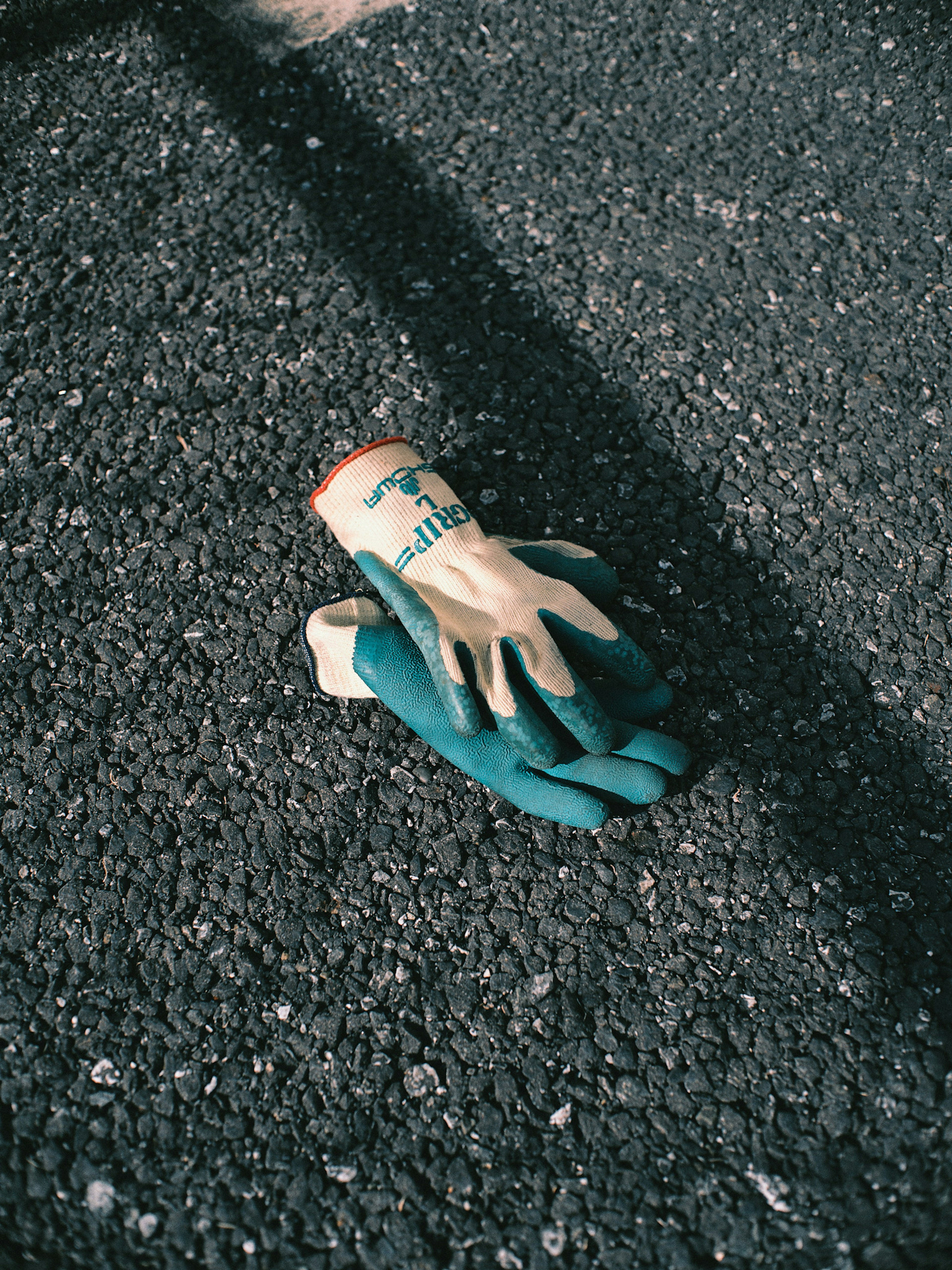 Green and white work gloves resting on the ground