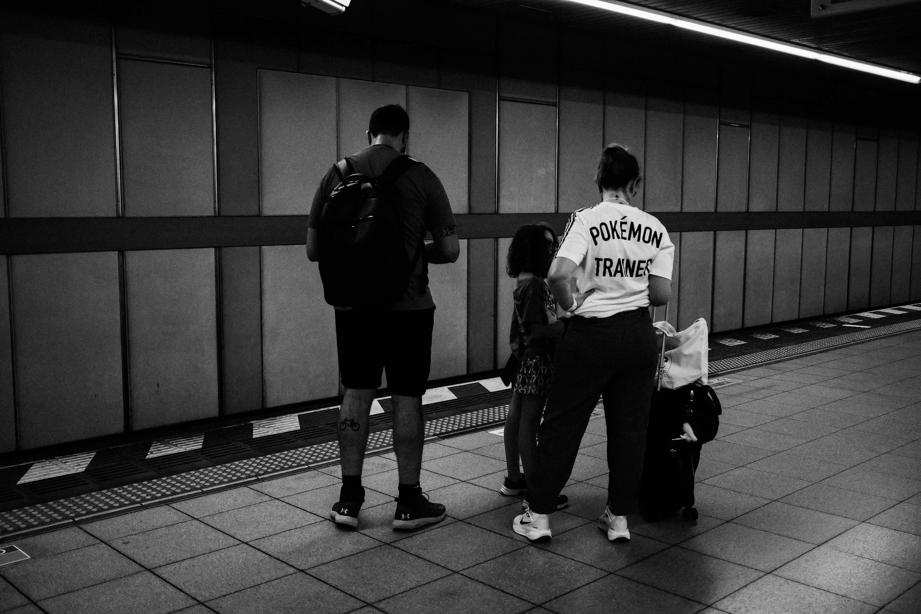 Dos hombres y un niño esperando en una plataforma de metro